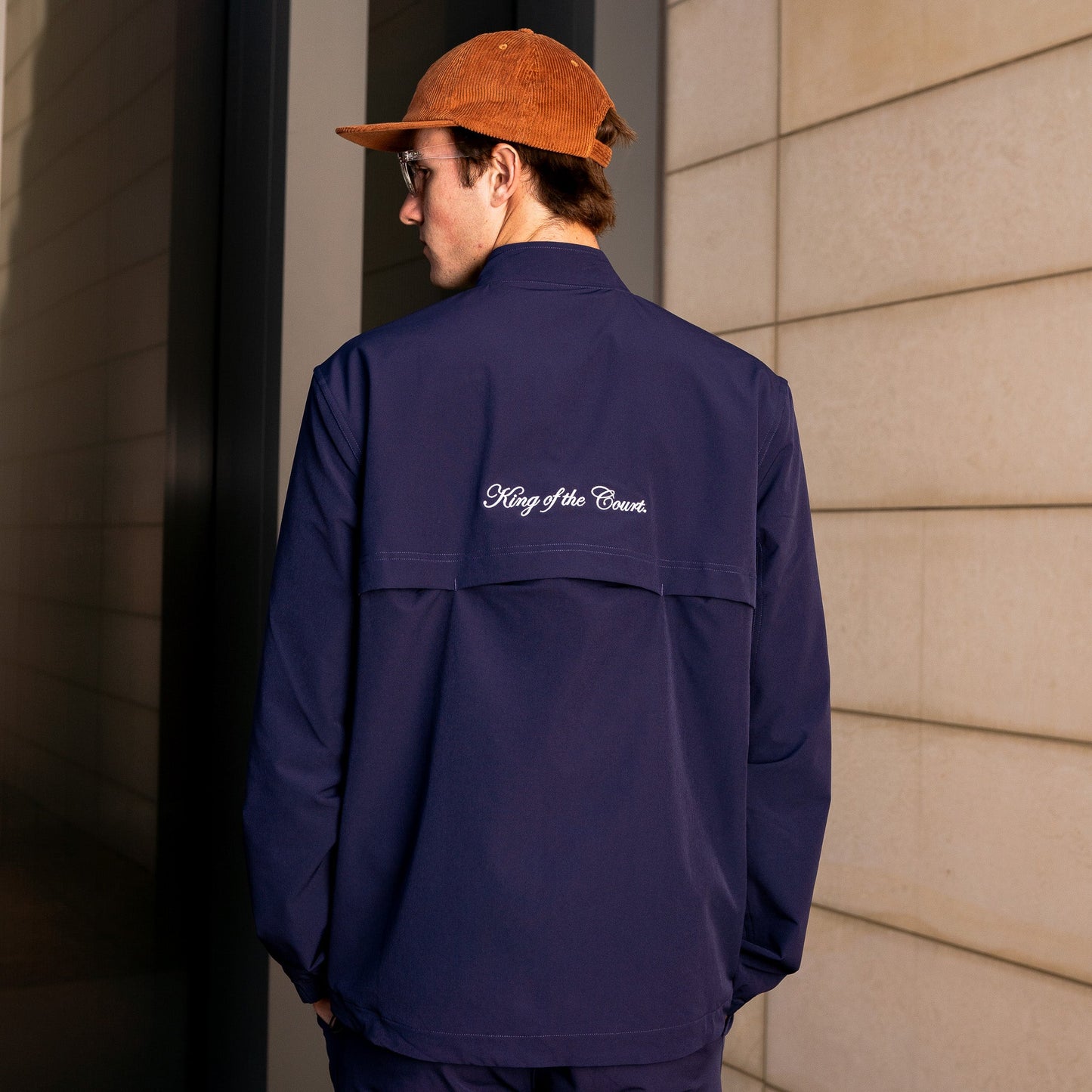Model wearing Sigrún match tennis jacket in navy back view.