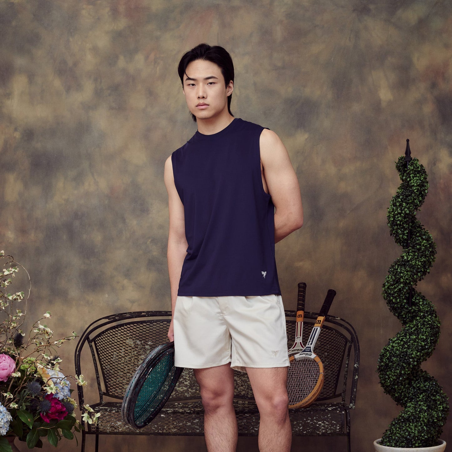 Model wearing Sigrún tank top in navy holding a tennis racquet.