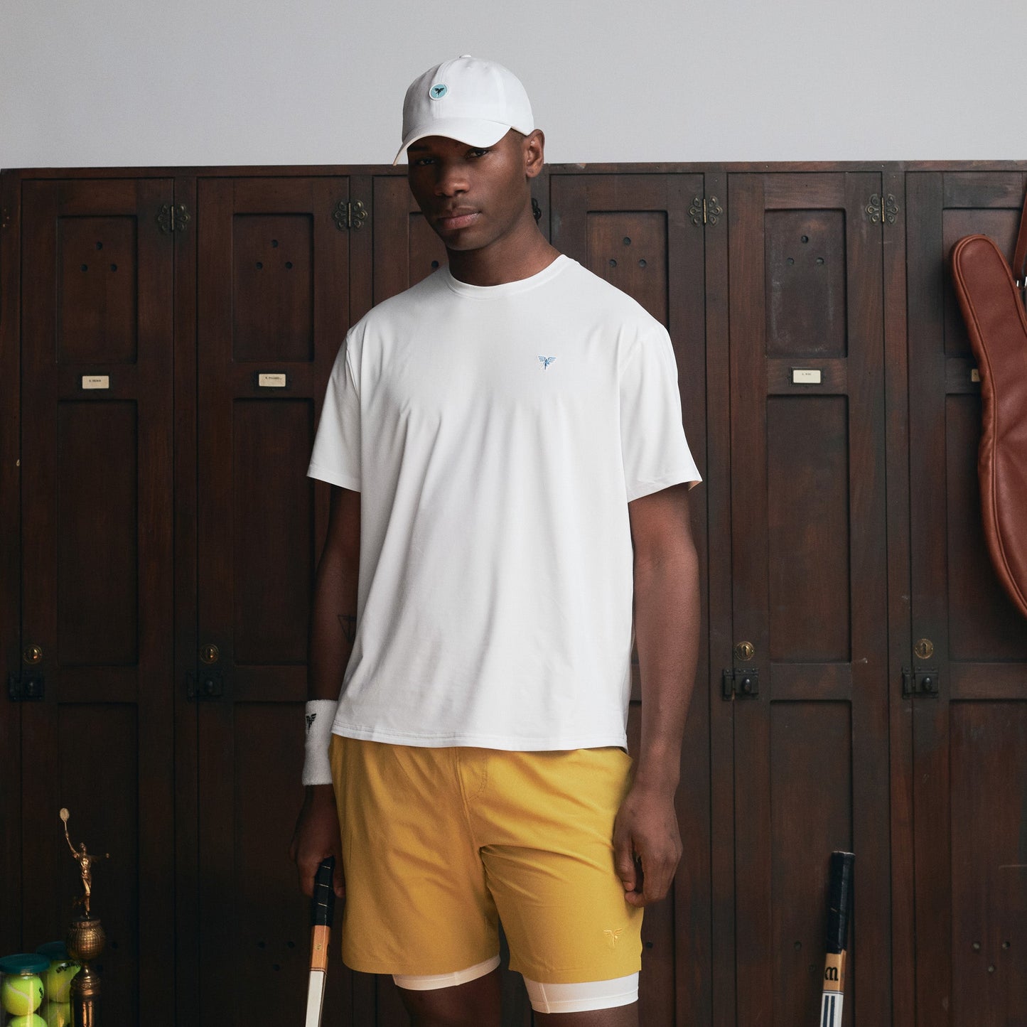 Model wearing Sigrún white match tee and white hat holding a tennis racquet.
