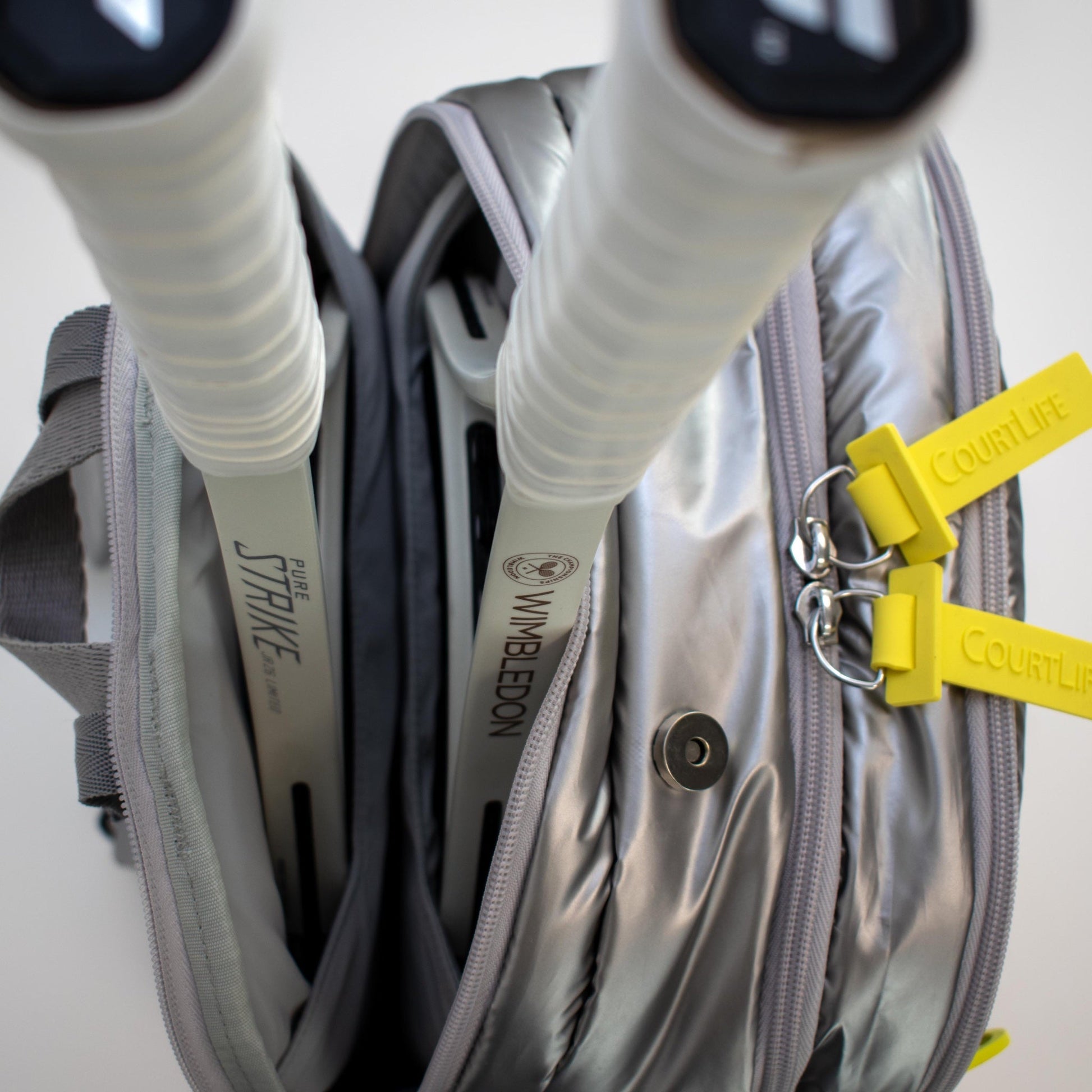 Gray tennis bag with rackets and Wimbledon keychain on a white background