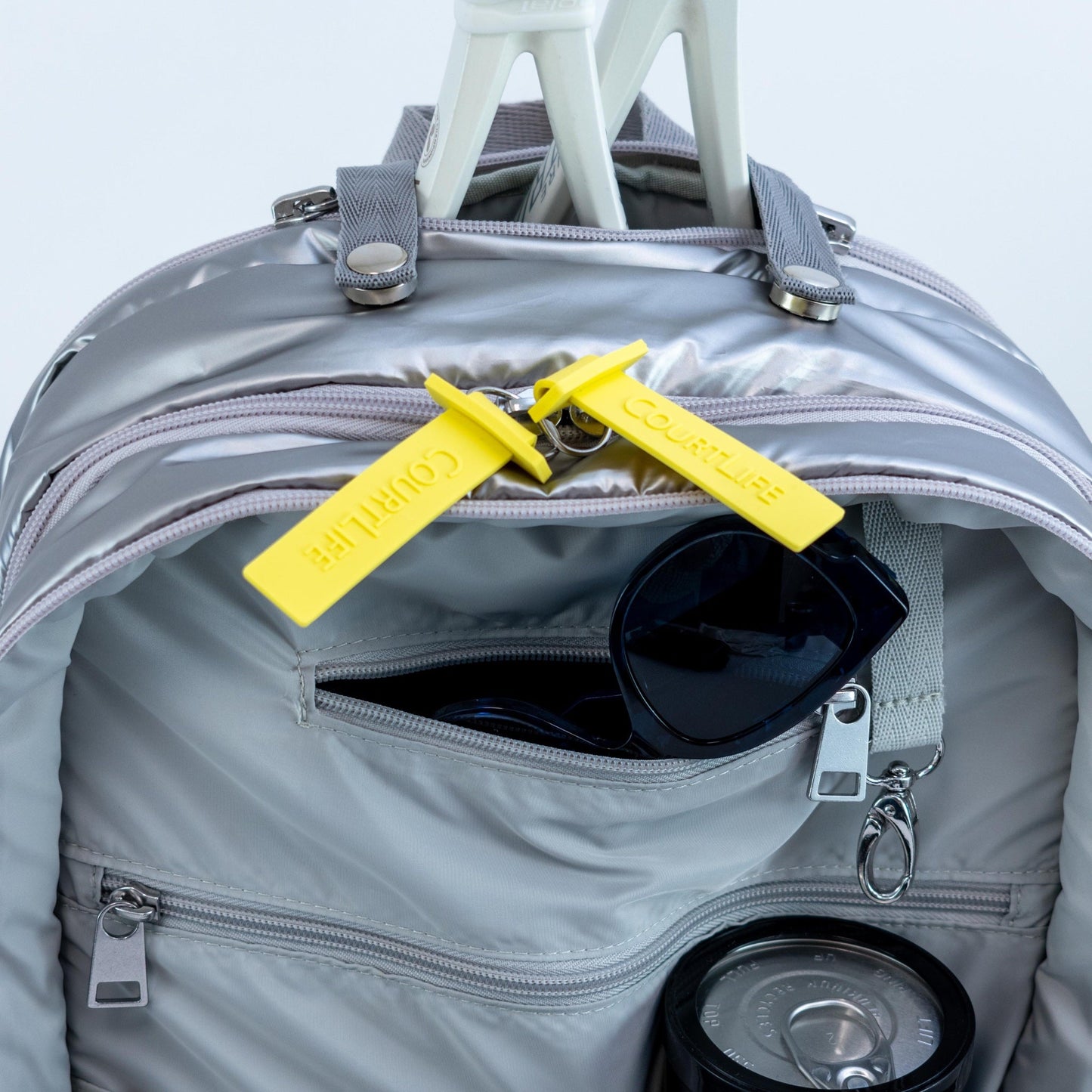 Gray backpack with sunglasses and a yellow tag on a light gray background