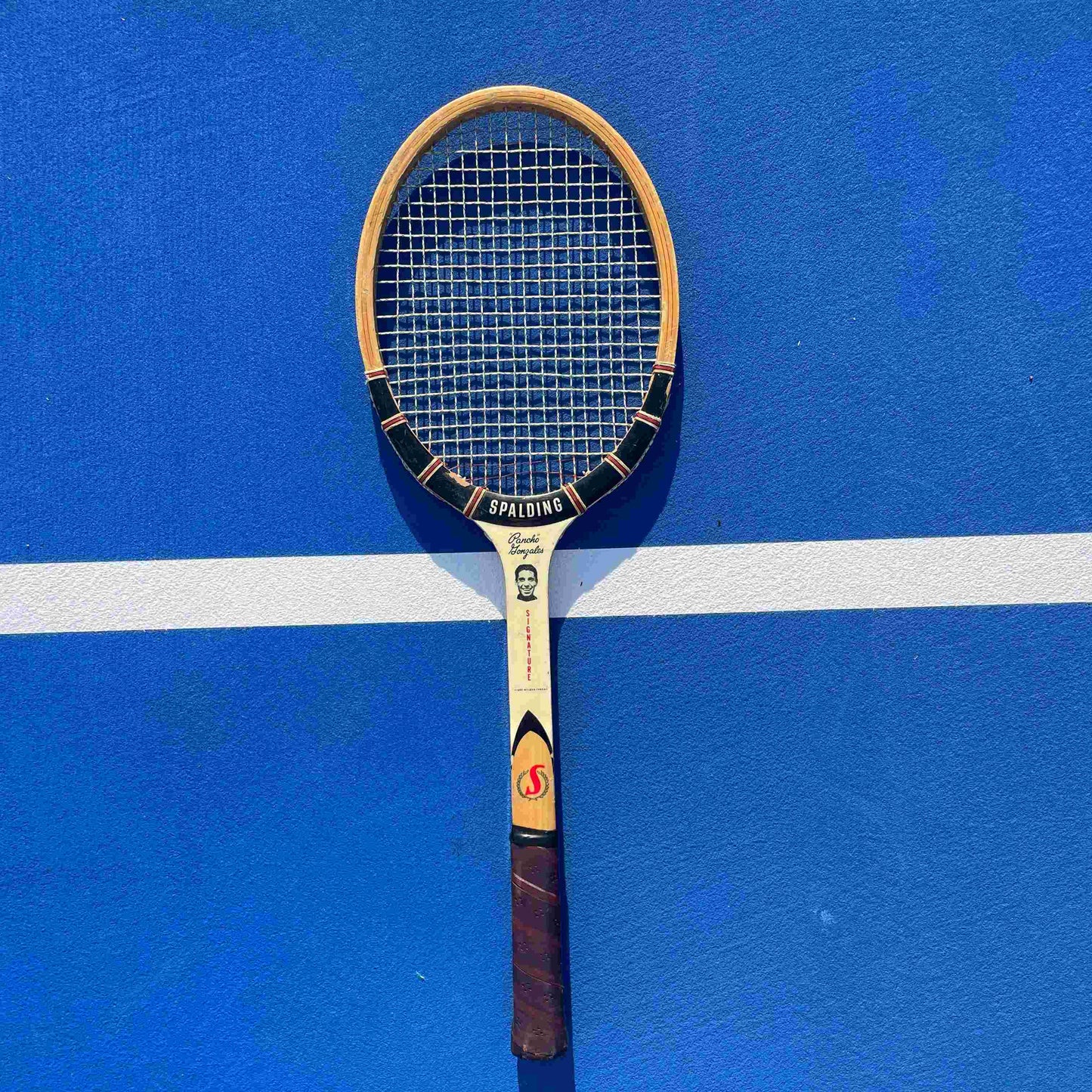 Vintage Spalding tennis racket on a blue court
