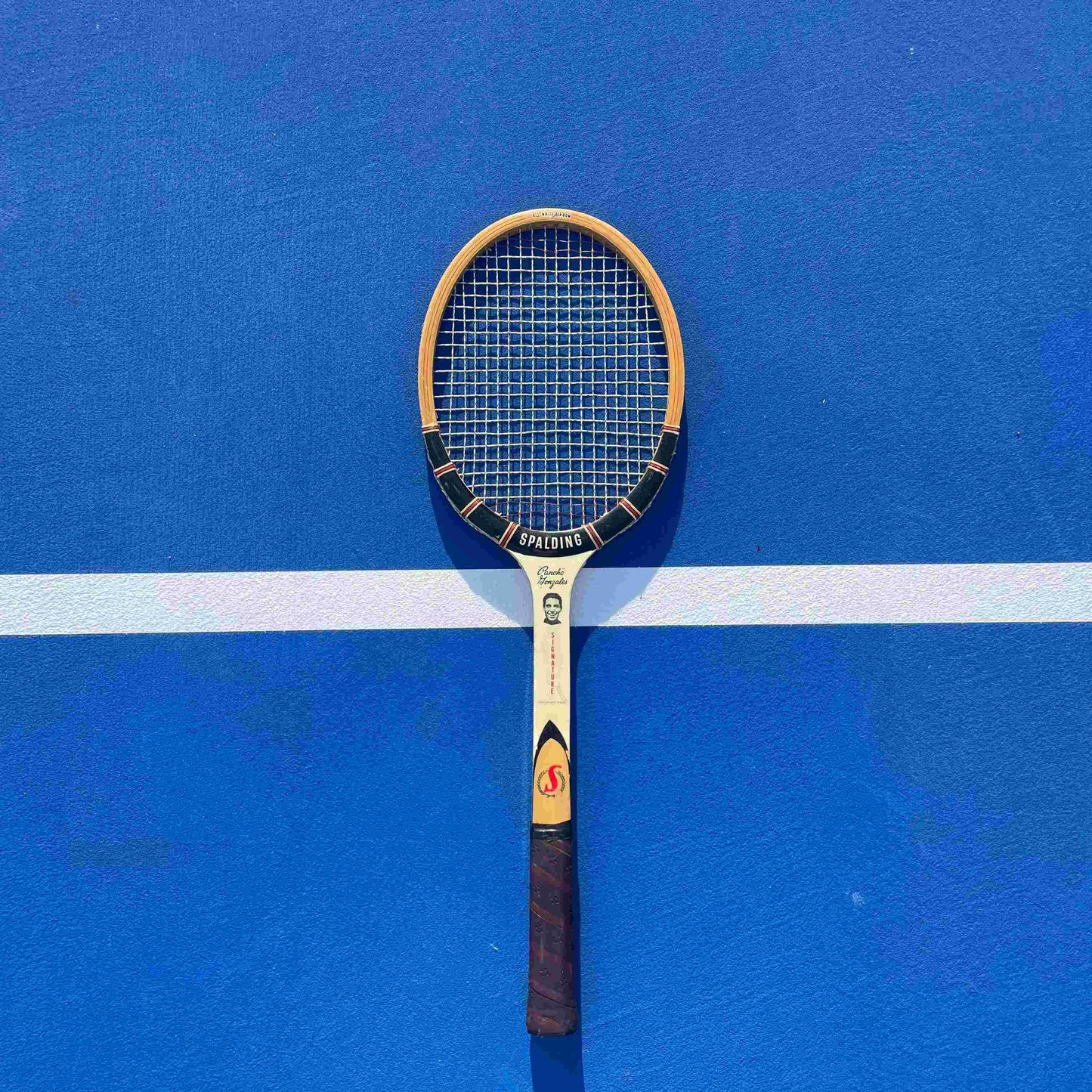 Tennis racket on a blue court with visible strings