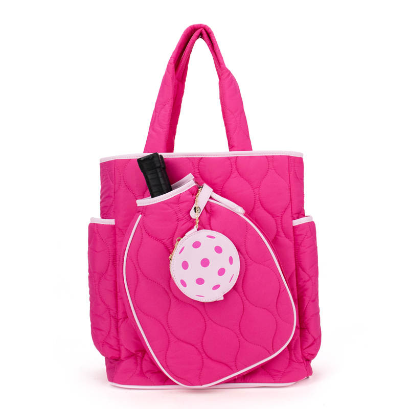 Pink quilted pickleball tote bag with a white polka dot charm on a white background
