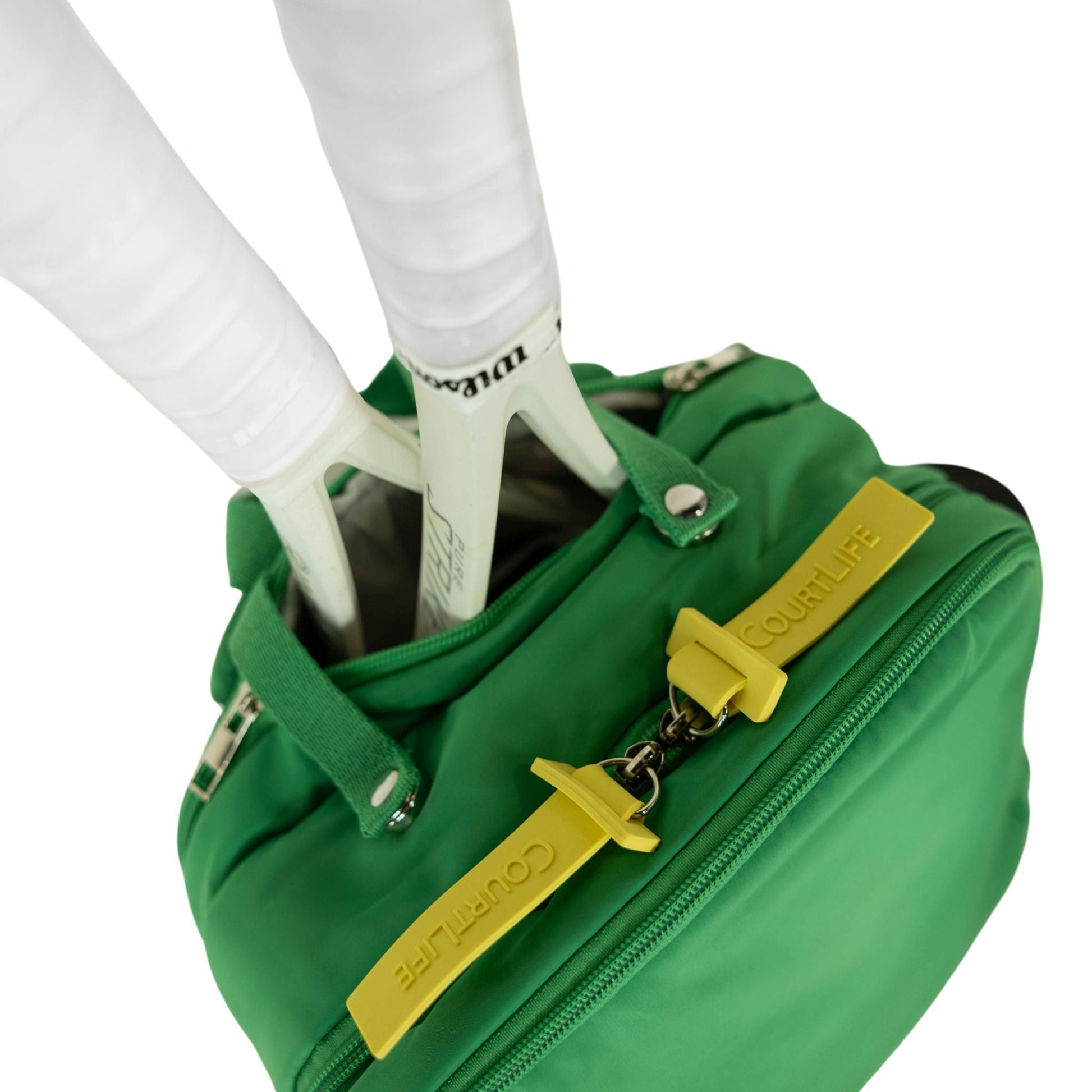 Green bag with yellow accents held by a person wearing white shoes on a white background