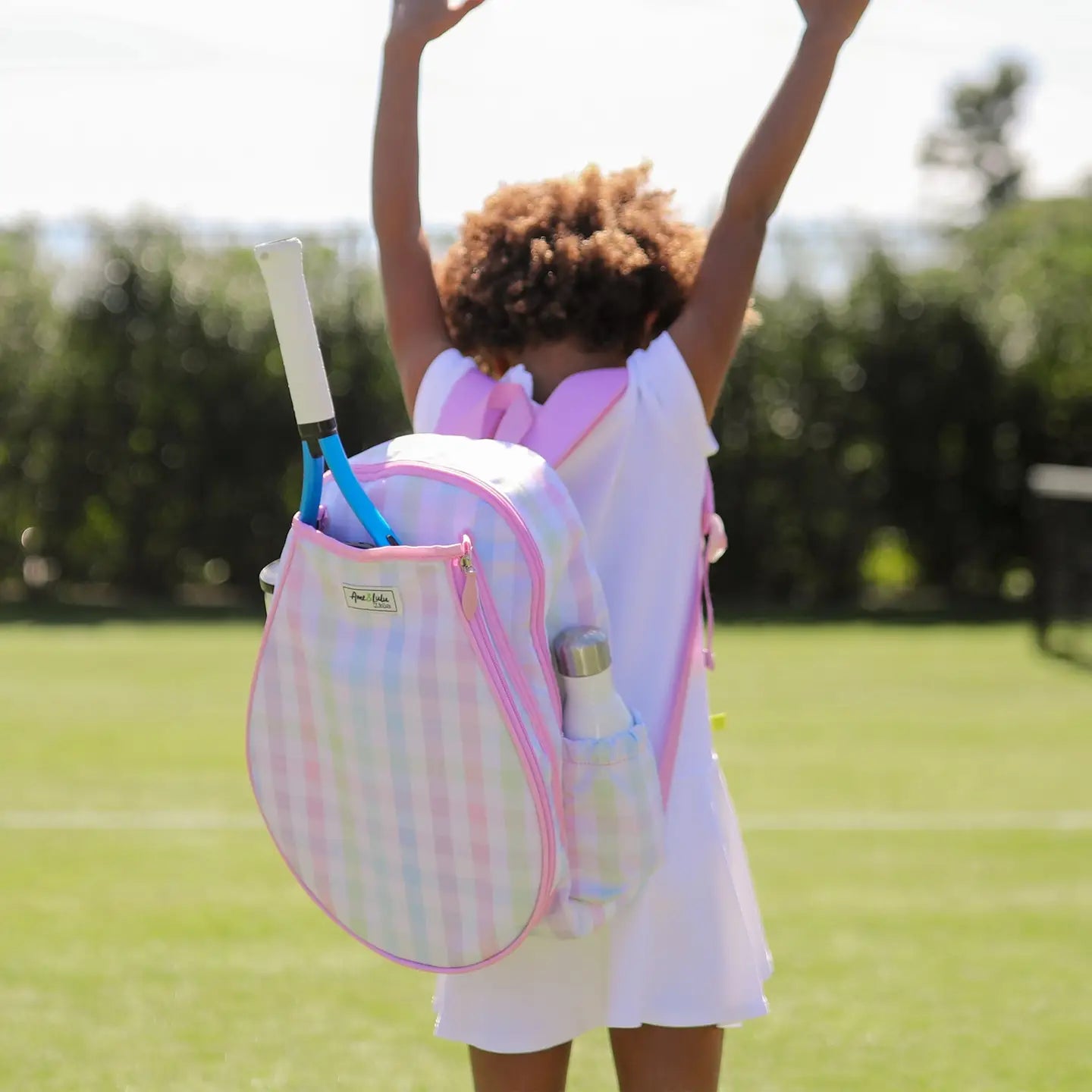 Child with a colorful tennis backpack on a tennis court