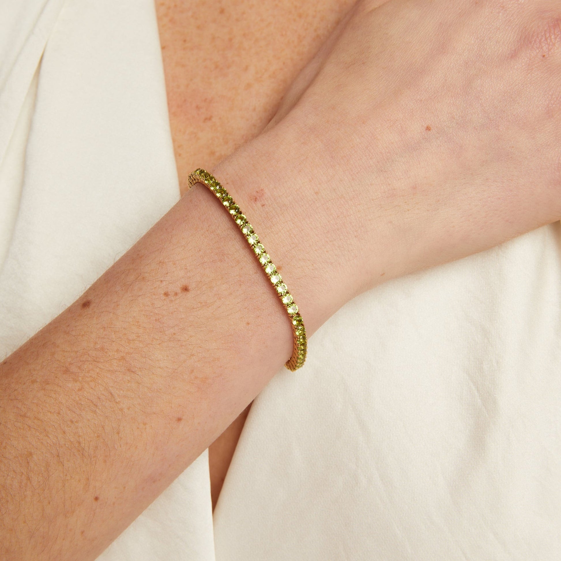 Gold bracelet on a person's wrist with a neutral background