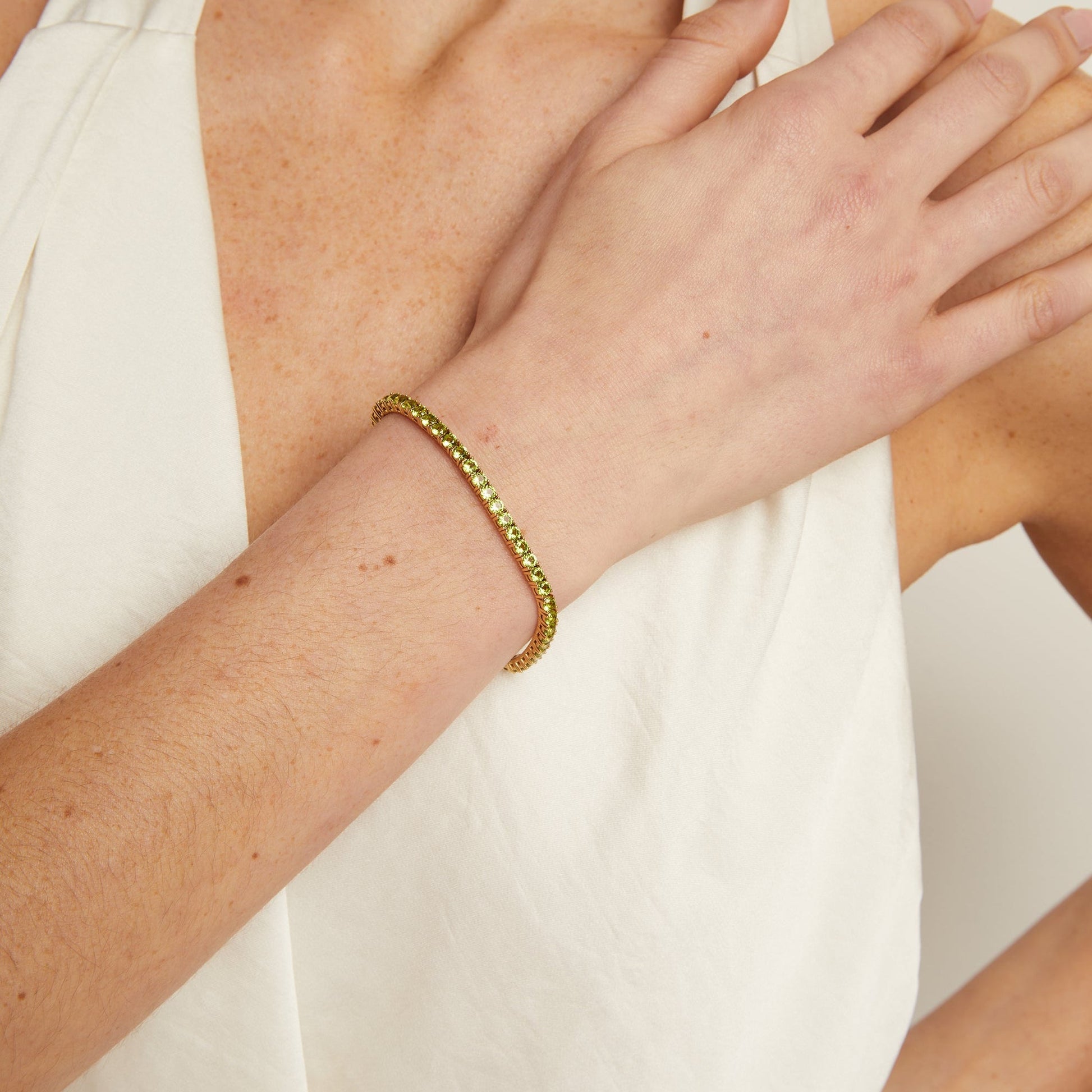 Gold bracelet on a wrist with a neutral background
