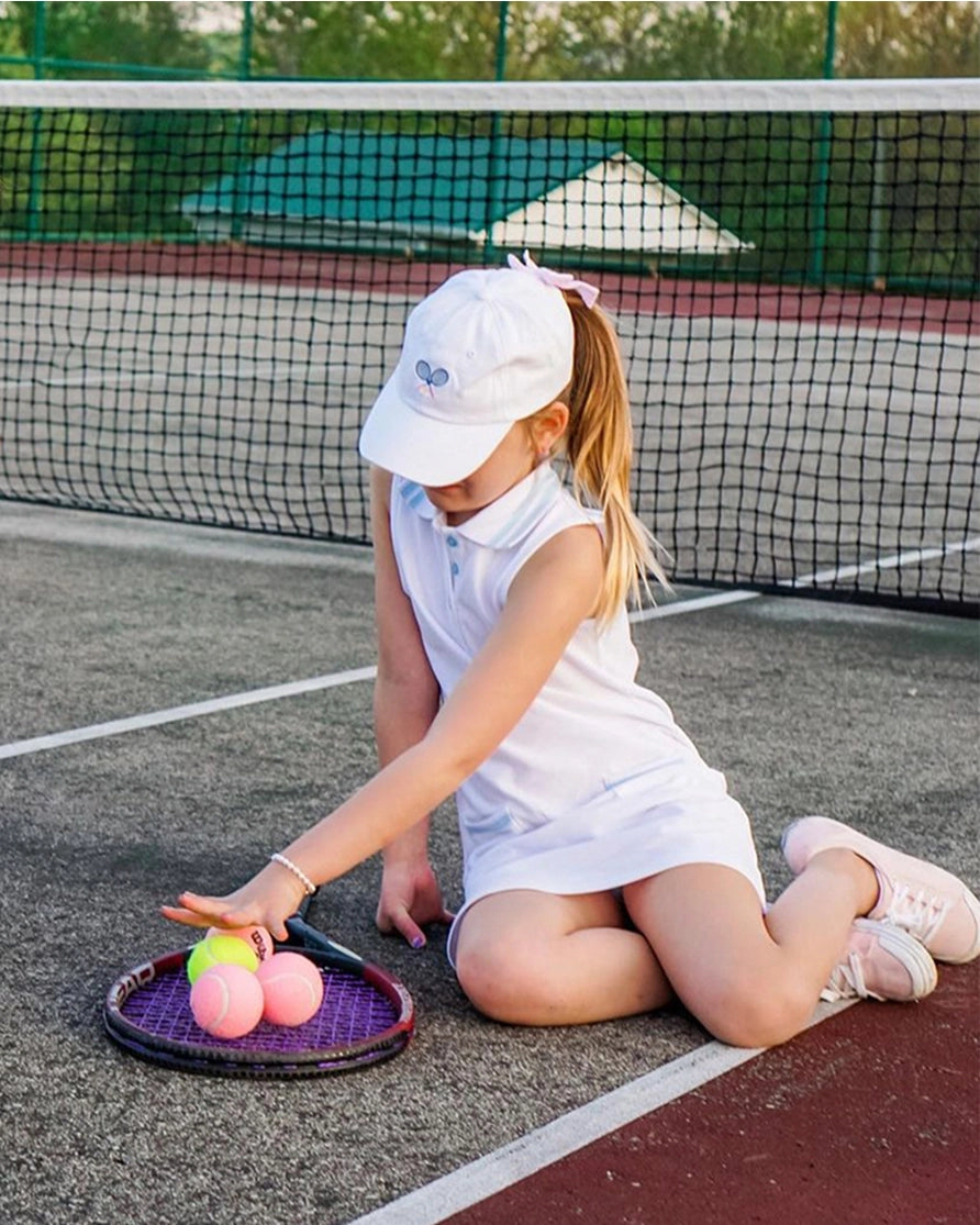 Young girl on a tennis court with a racket and balls