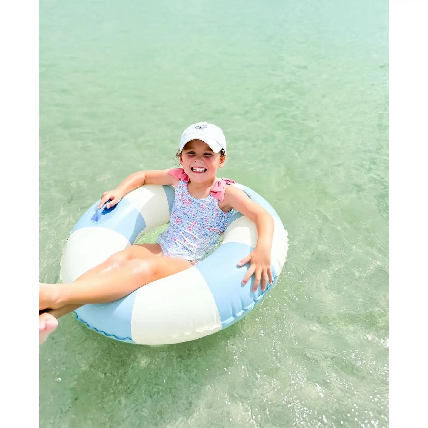 Child on a striped inflatable tube in clear water