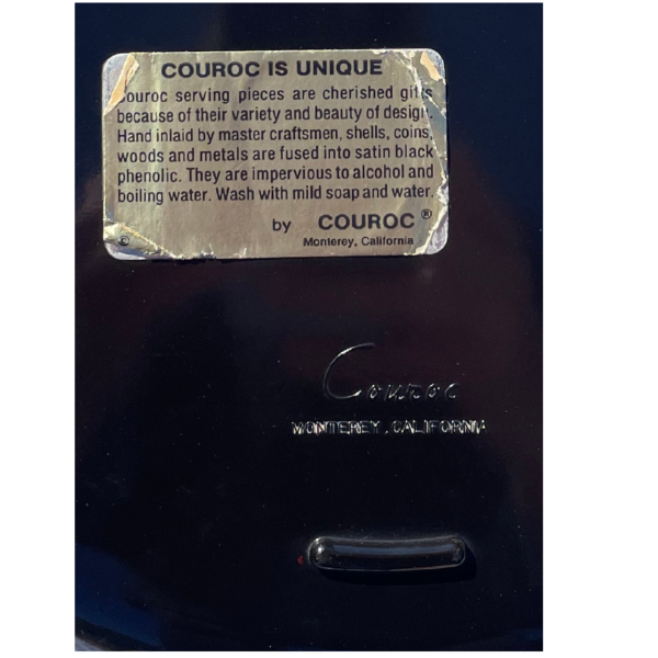 Close-up of a metal tag with text and branding on a dark background