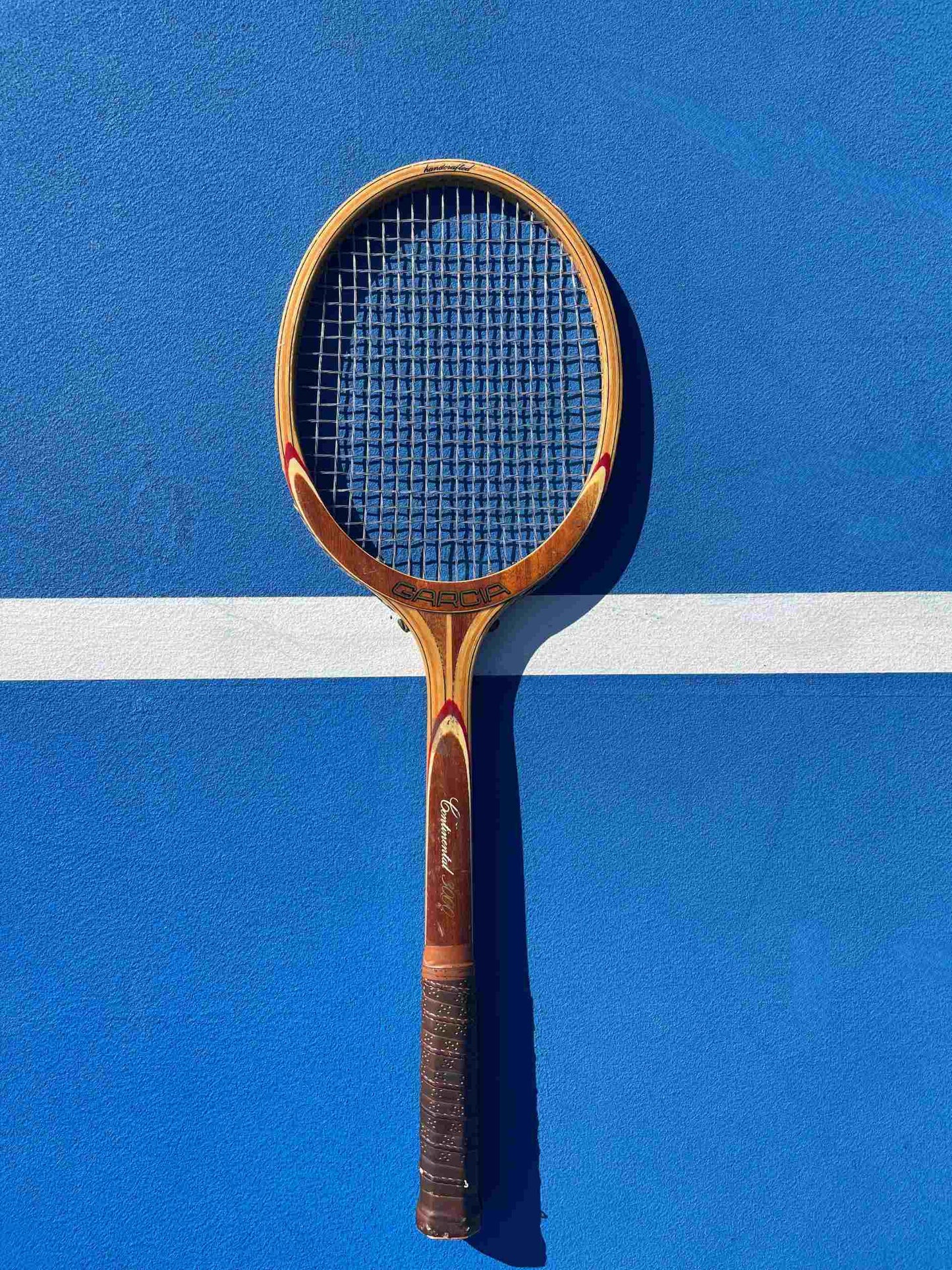 Garcia Continental Wood Tennis Racquet on blue tennis court.