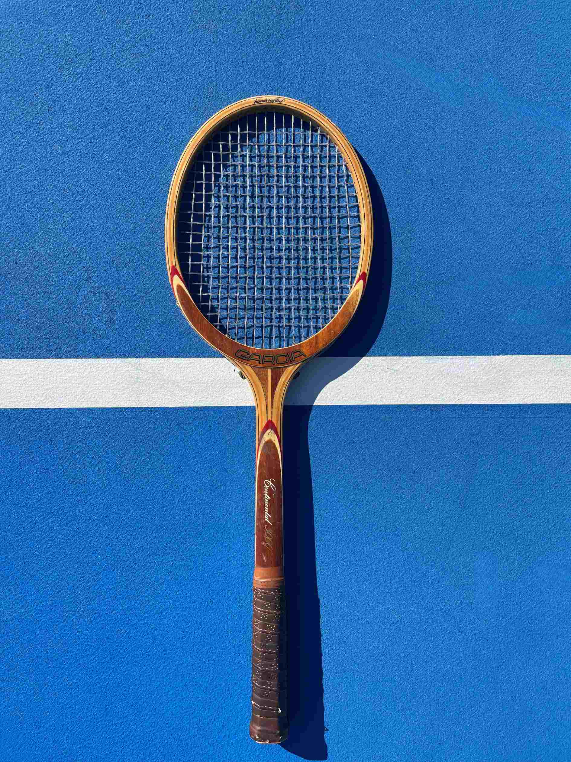 Garcia Continental Wood Tennis Racquet on blue tennis court.