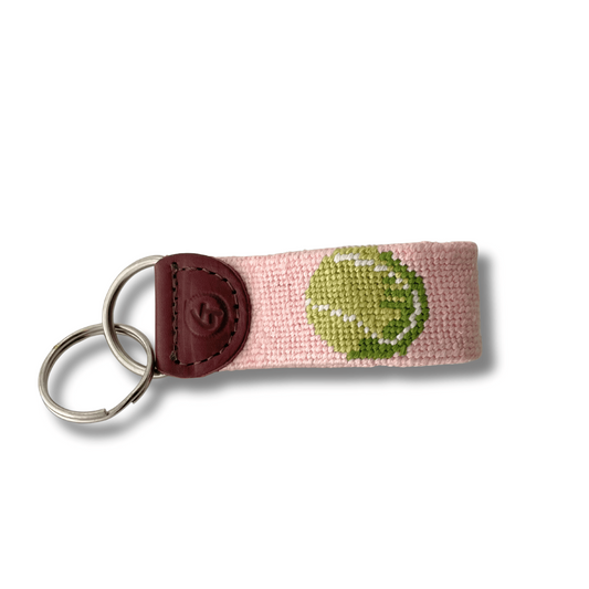 Keychain with pink strap and green embroidered design on a white background