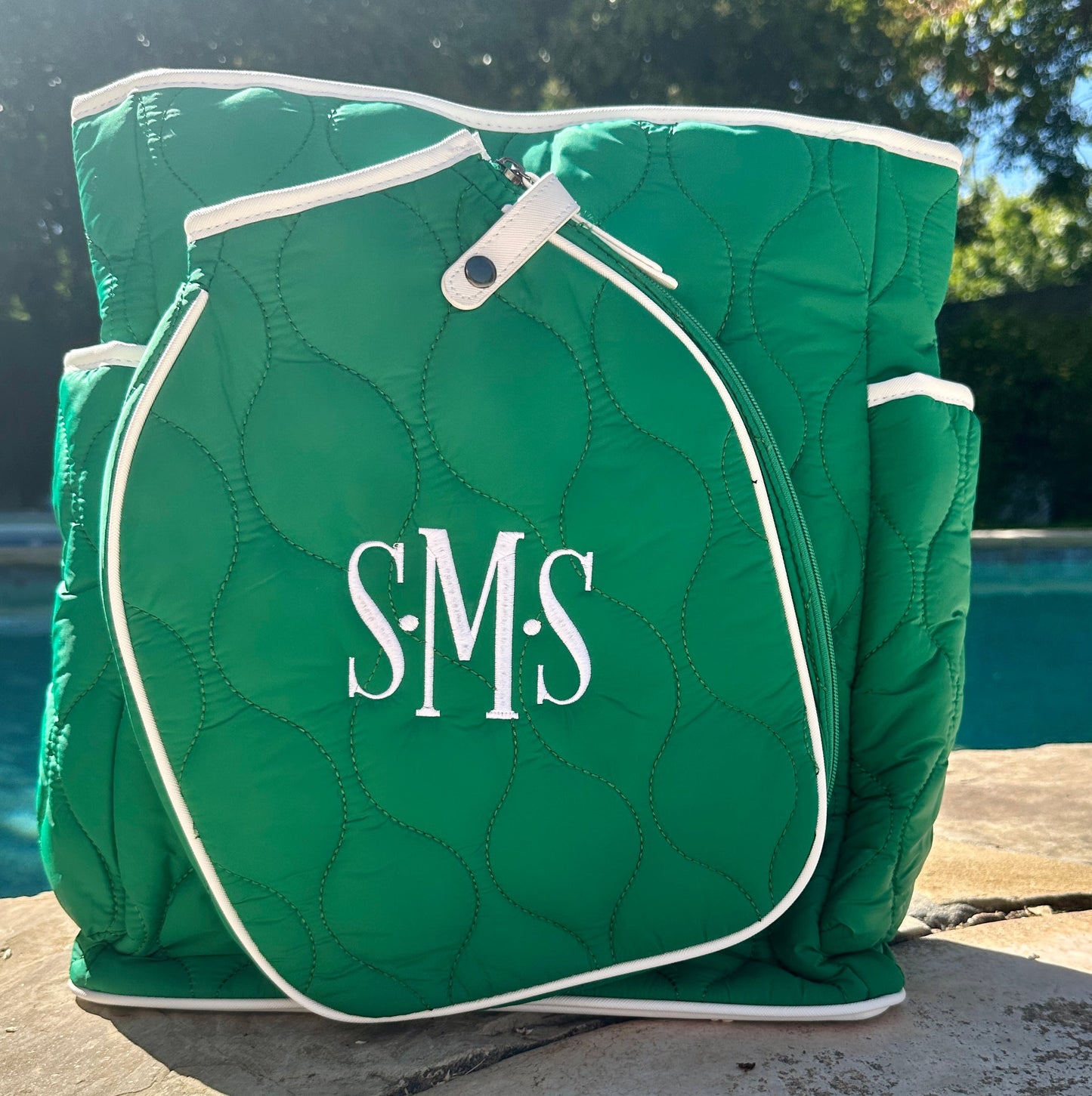Green quilted bag with 'S.M.S' monogram on a poolside background