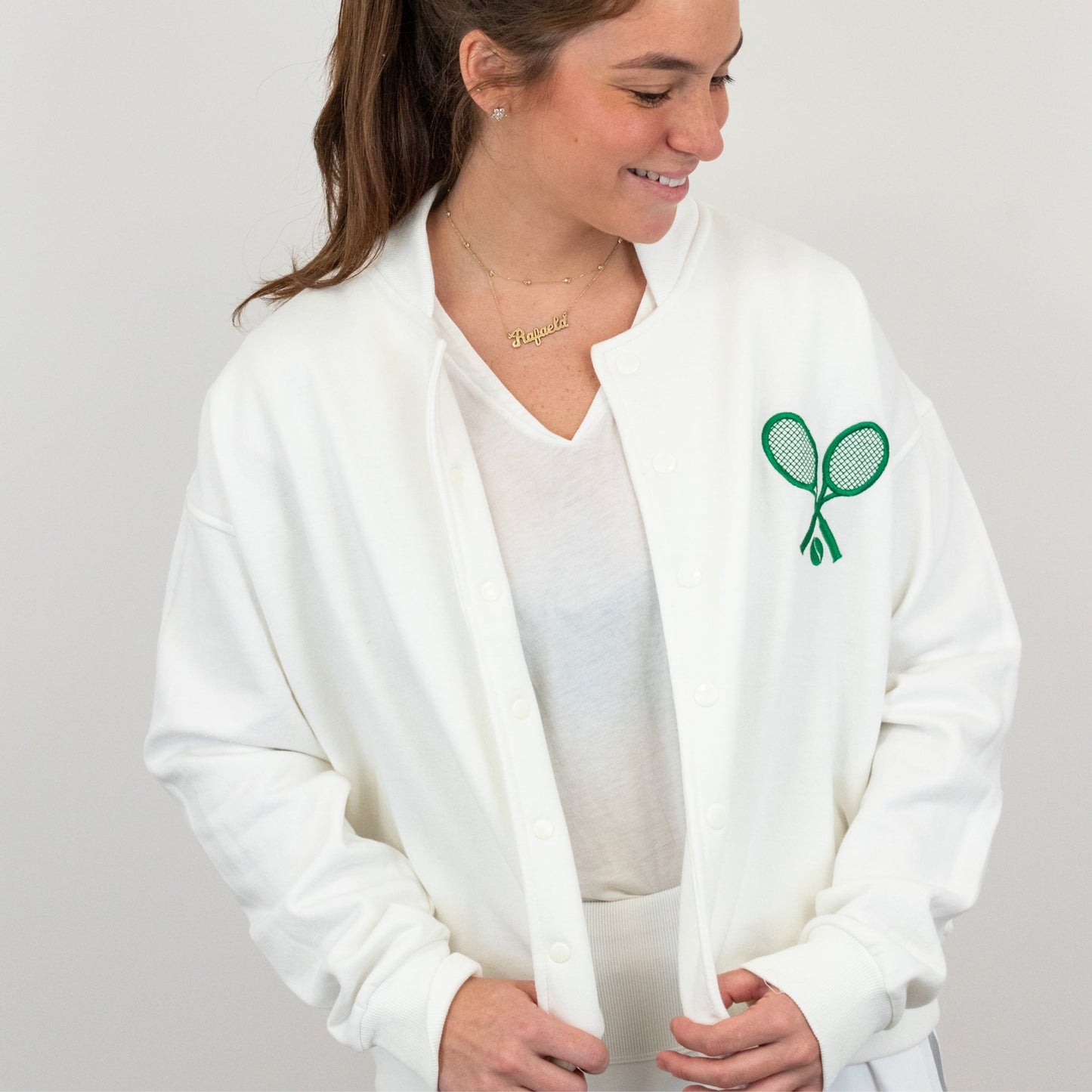 Woman wearing a white jacket with a green logo on a gray background