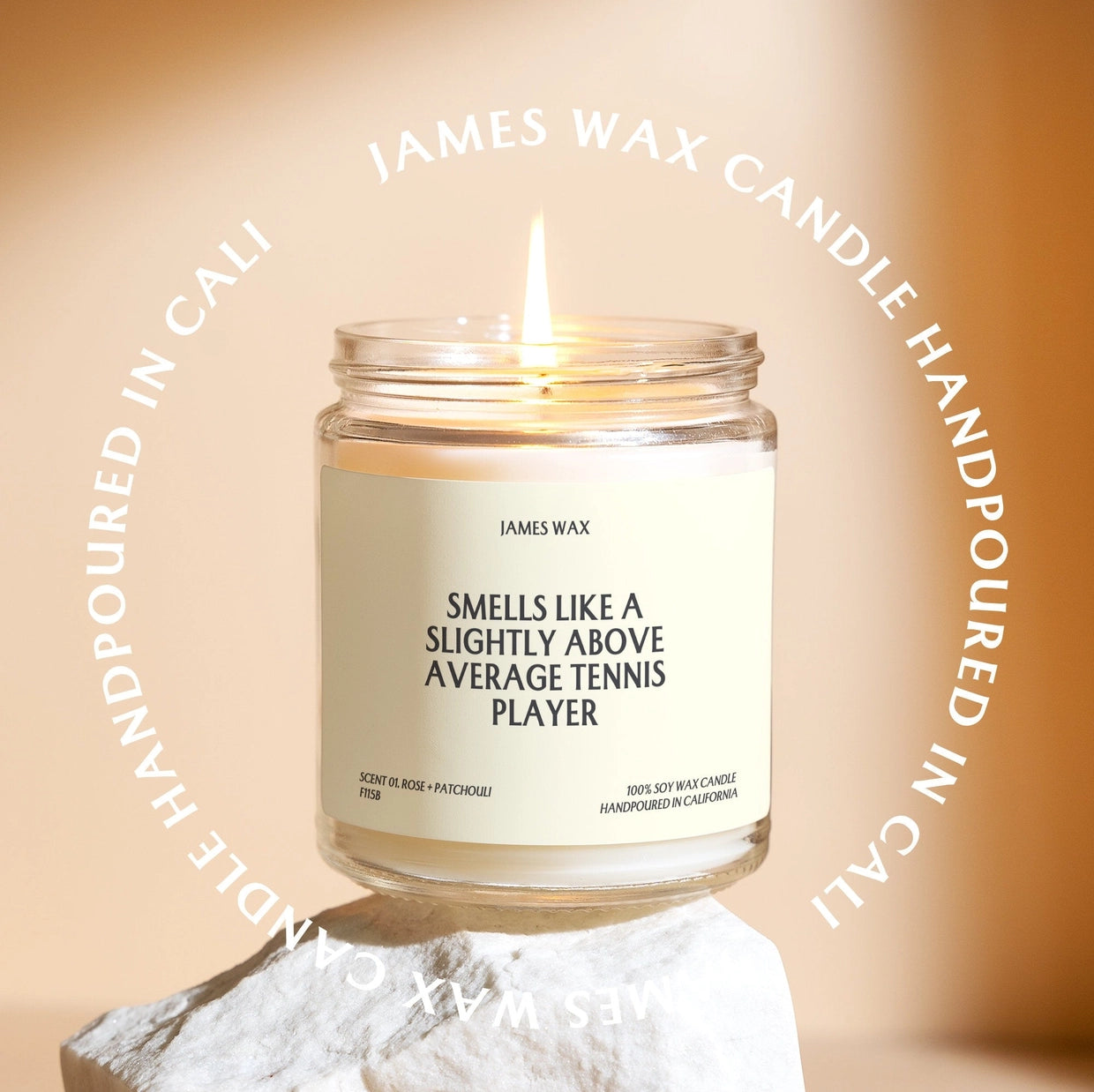 Burning candle with "smells like above average tennis player" on label sitting on rock. 