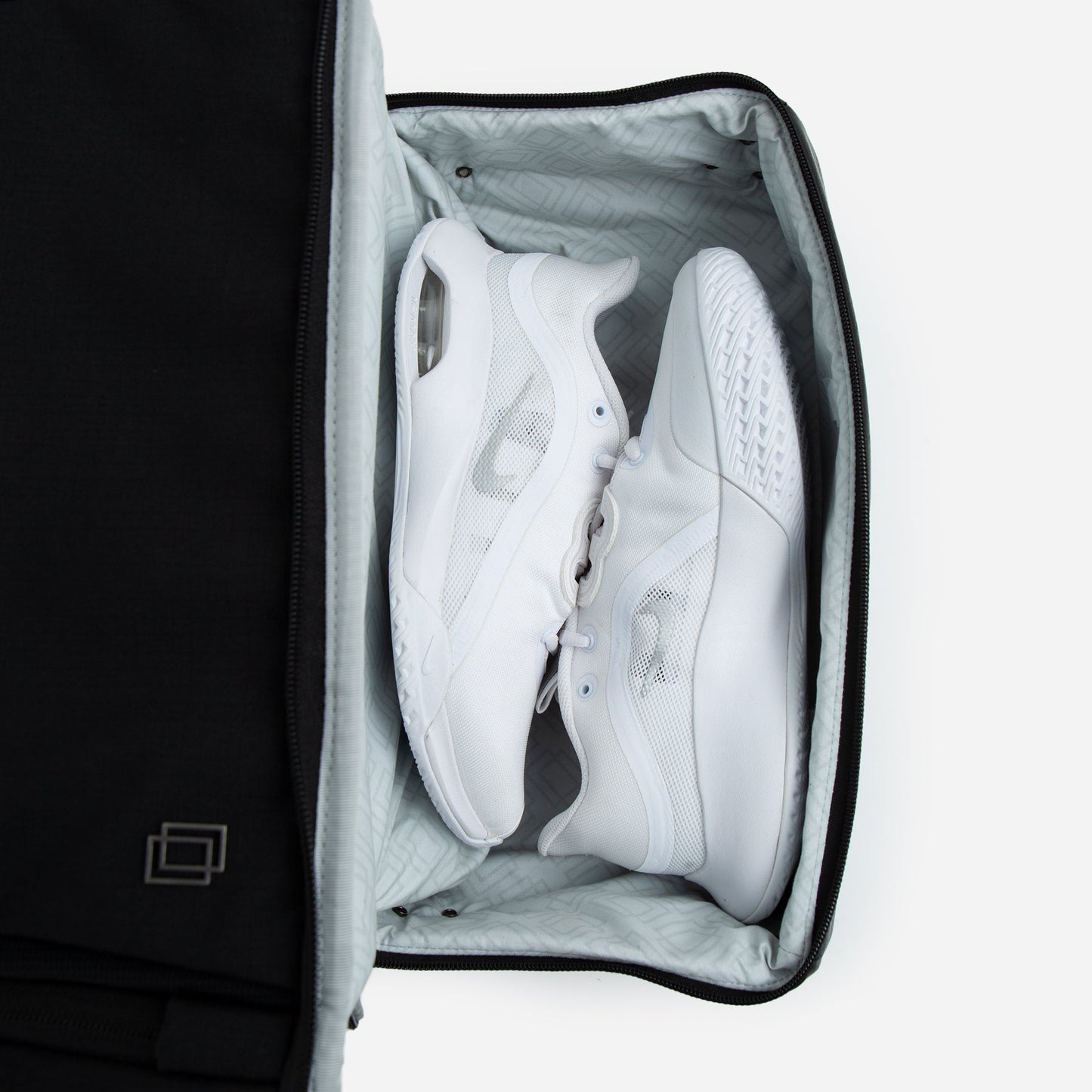 Black shoe bag with white sneakers inside on a white background