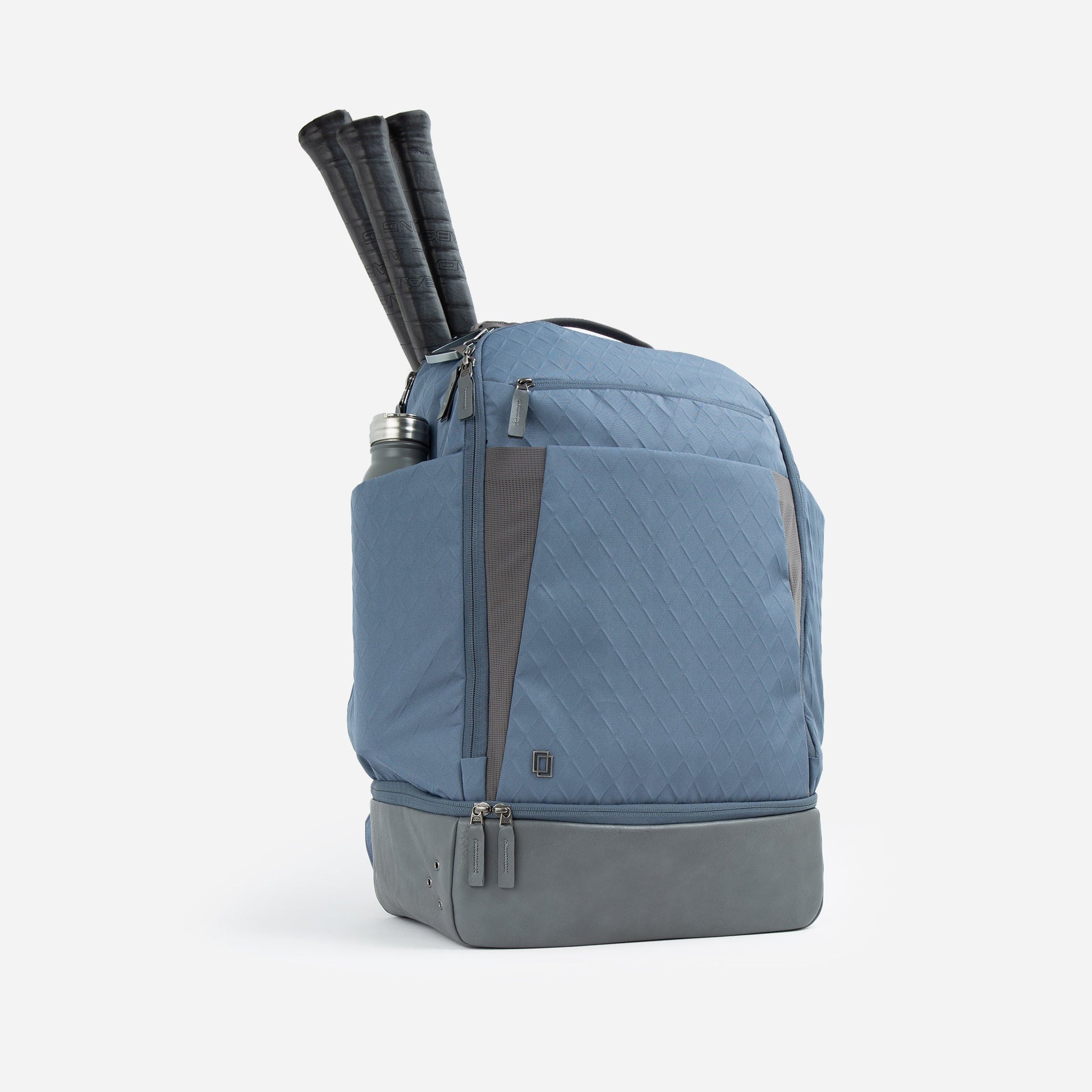 Blue and gray Doubletake tennis backpack with rolled-up yoga mat on a white background