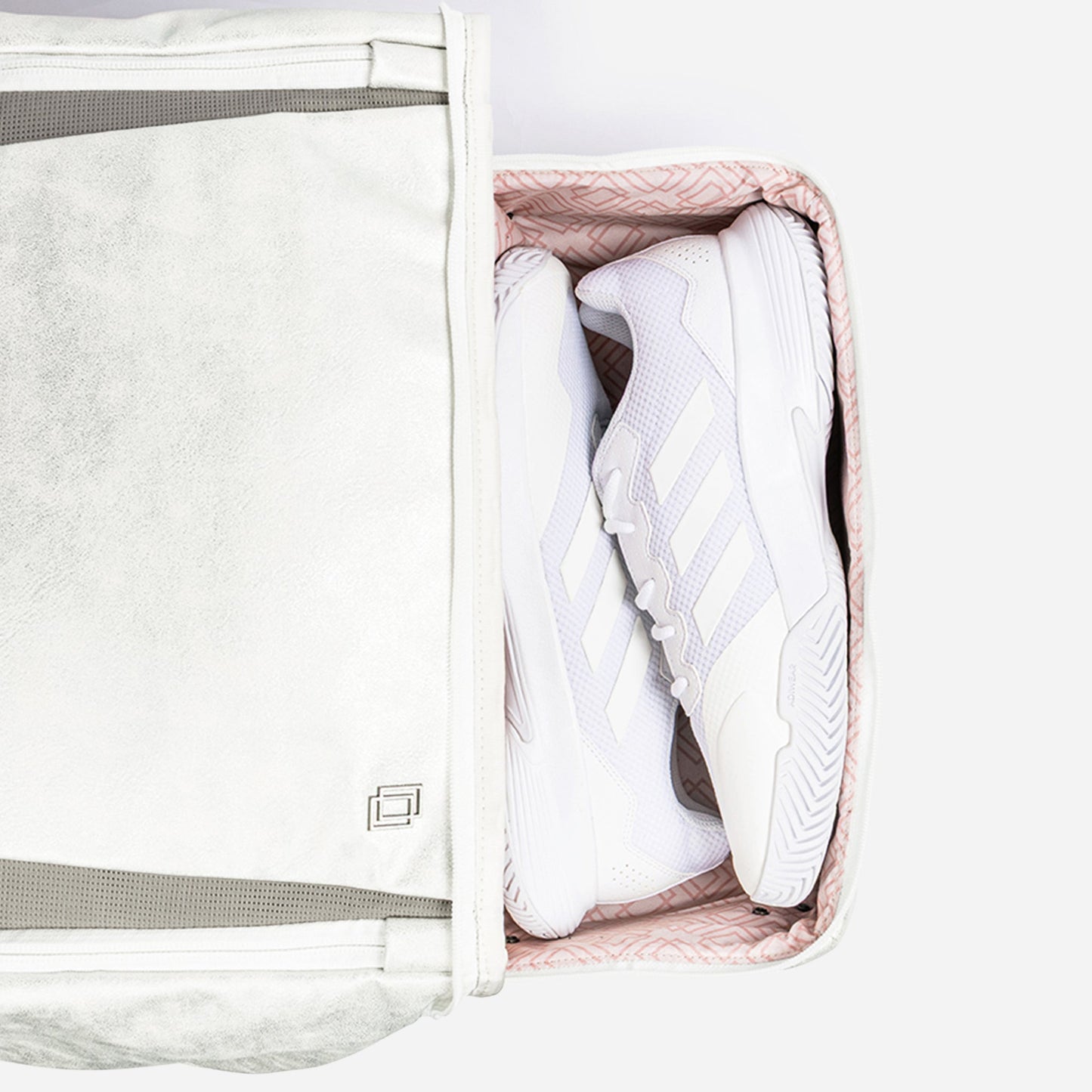 White sneakers inside a clear packing cube with a visible brand logo.