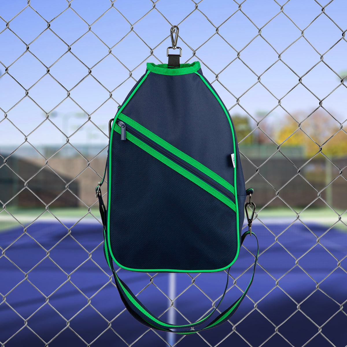Black and green  pickleball bag with a chain link fence and blue ground in the background