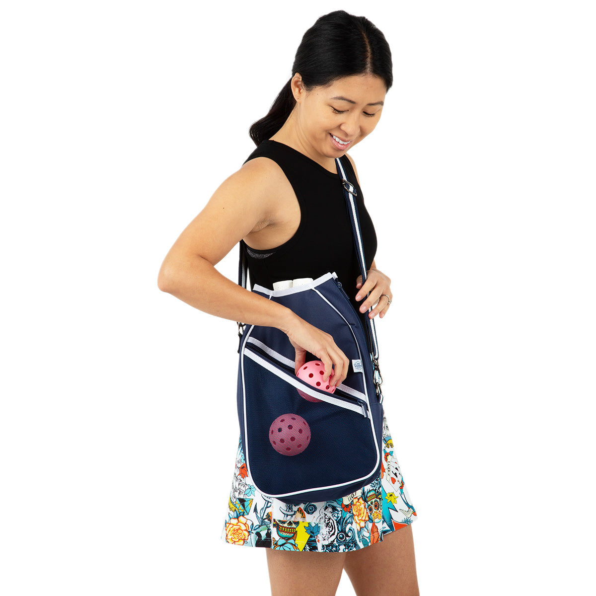Woman holding a navy blue pickleball bag with pink balls on a white background