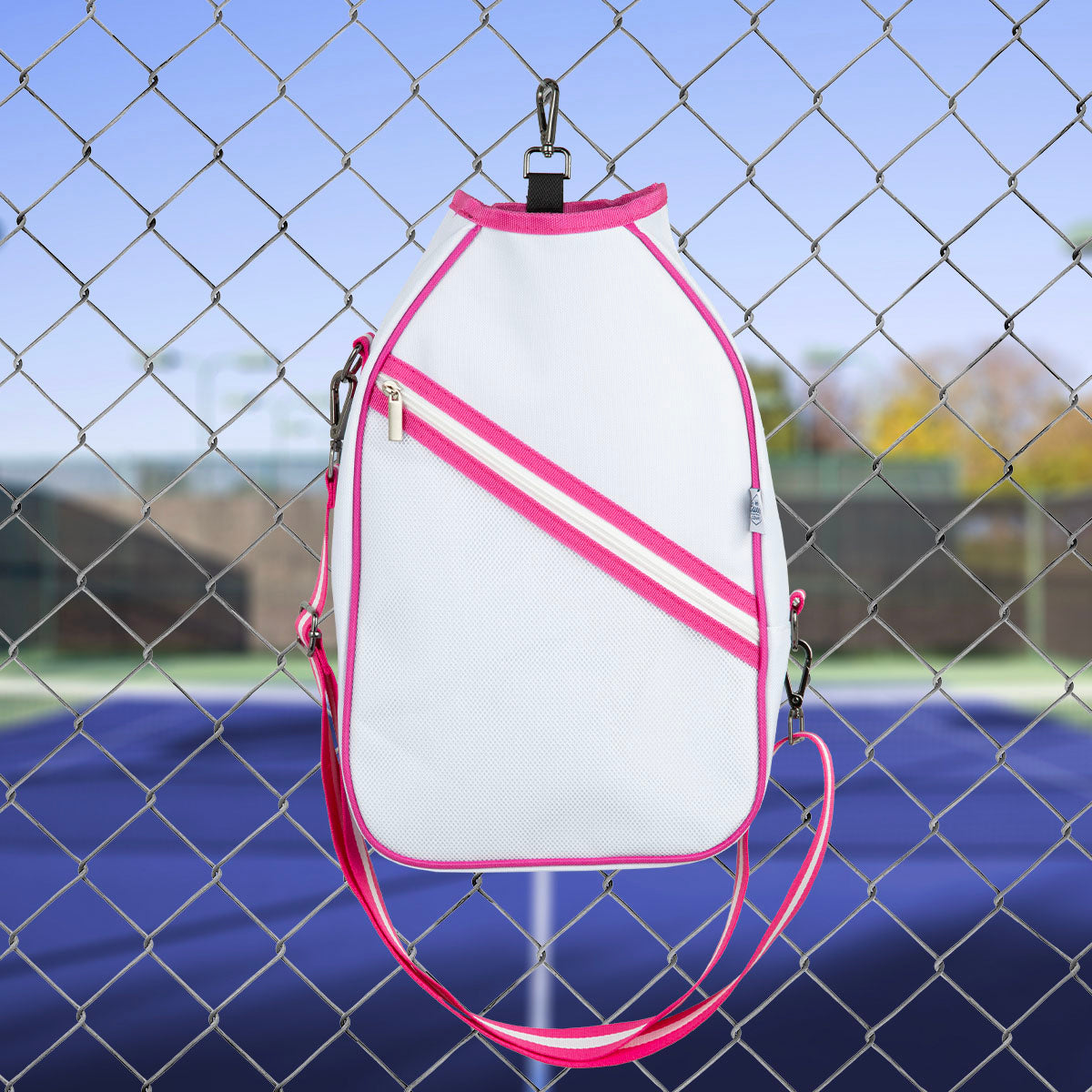 White and pink  pickleball bag with a chain link fence and tennis court in the background