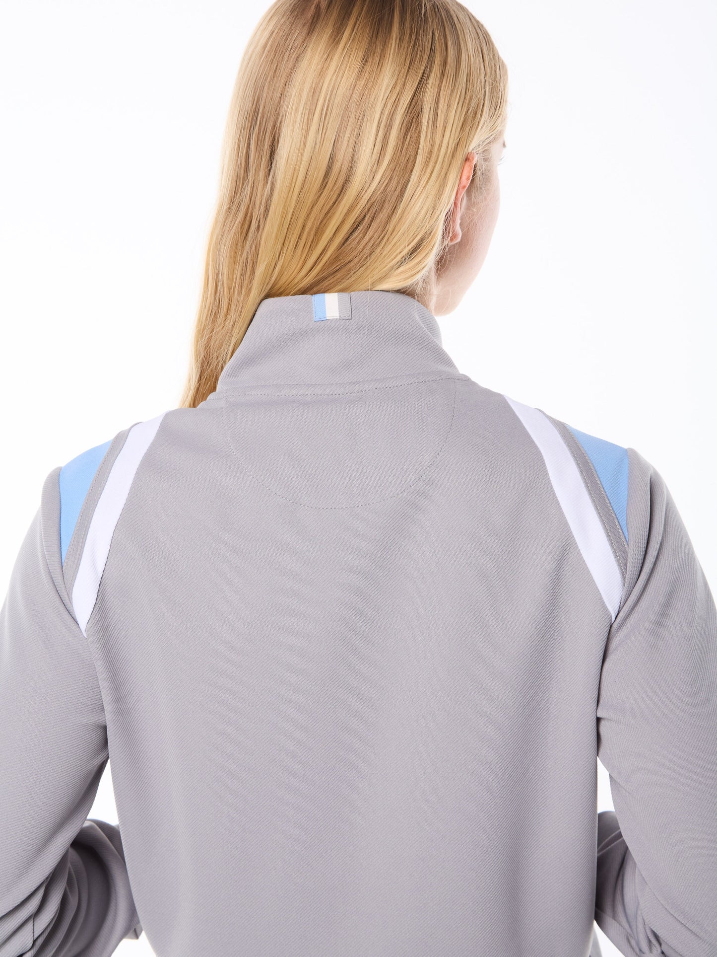 Person wearing a gray jacket with blue accents on a white background
