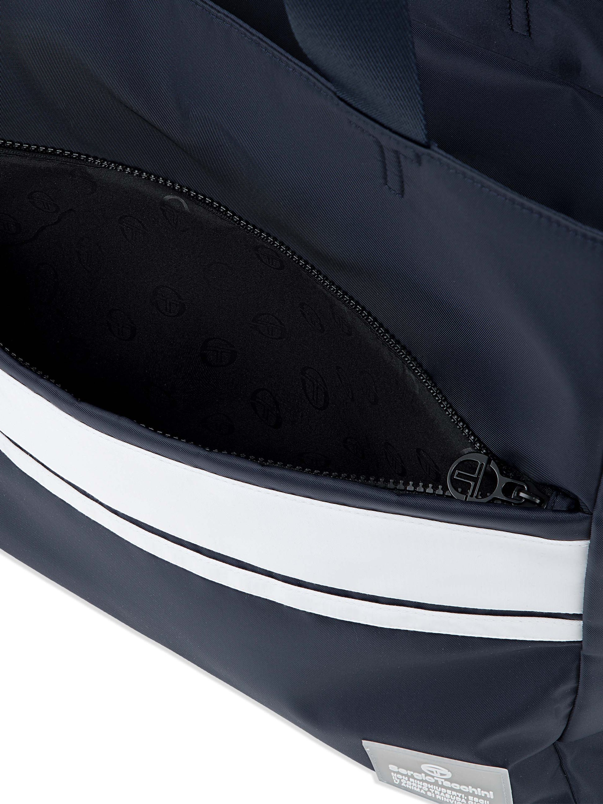 Close-up of a navy bag with white stripes and a visible brand label.