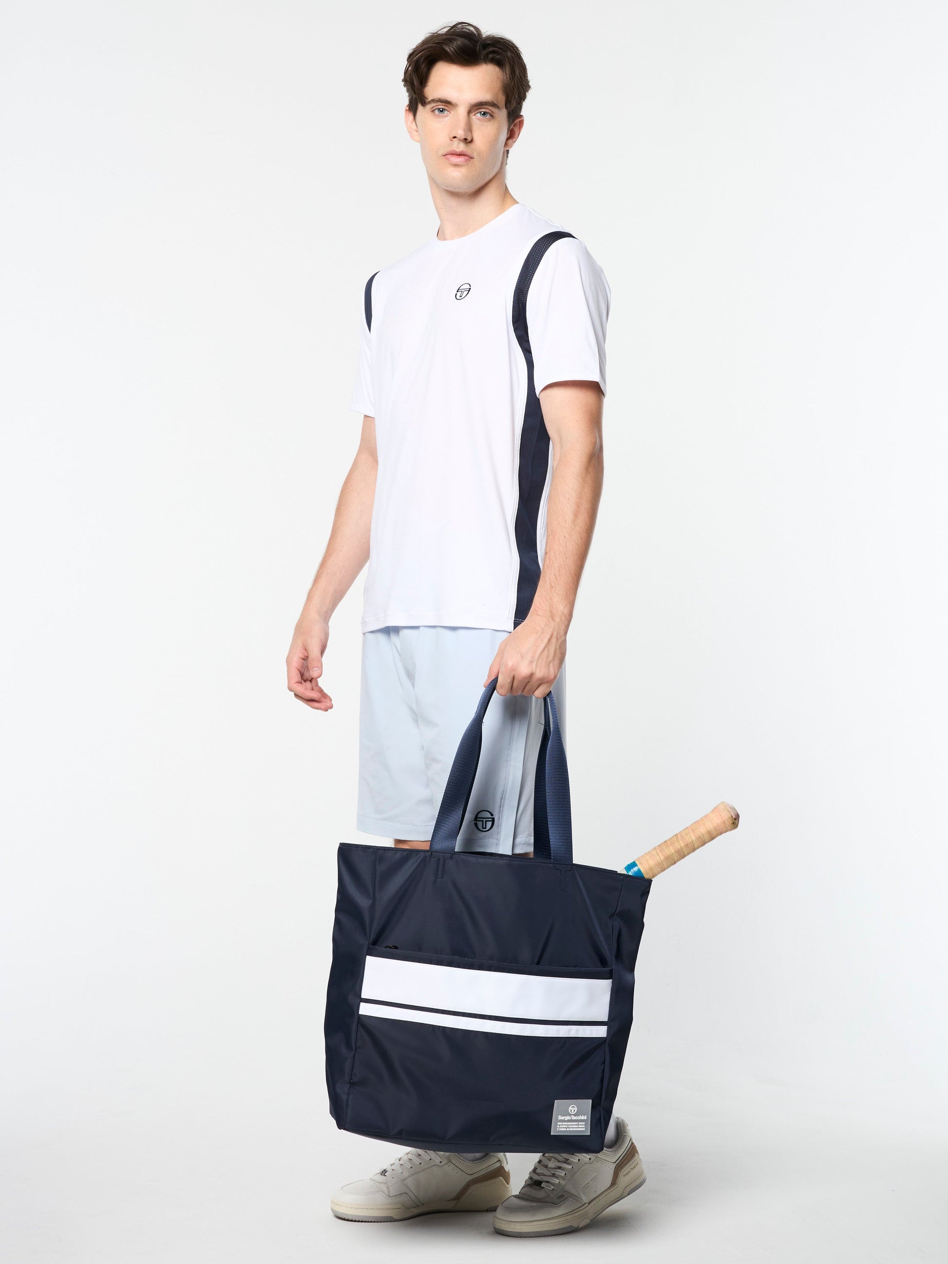Man holding a navy blue bag with white stripe on a white background