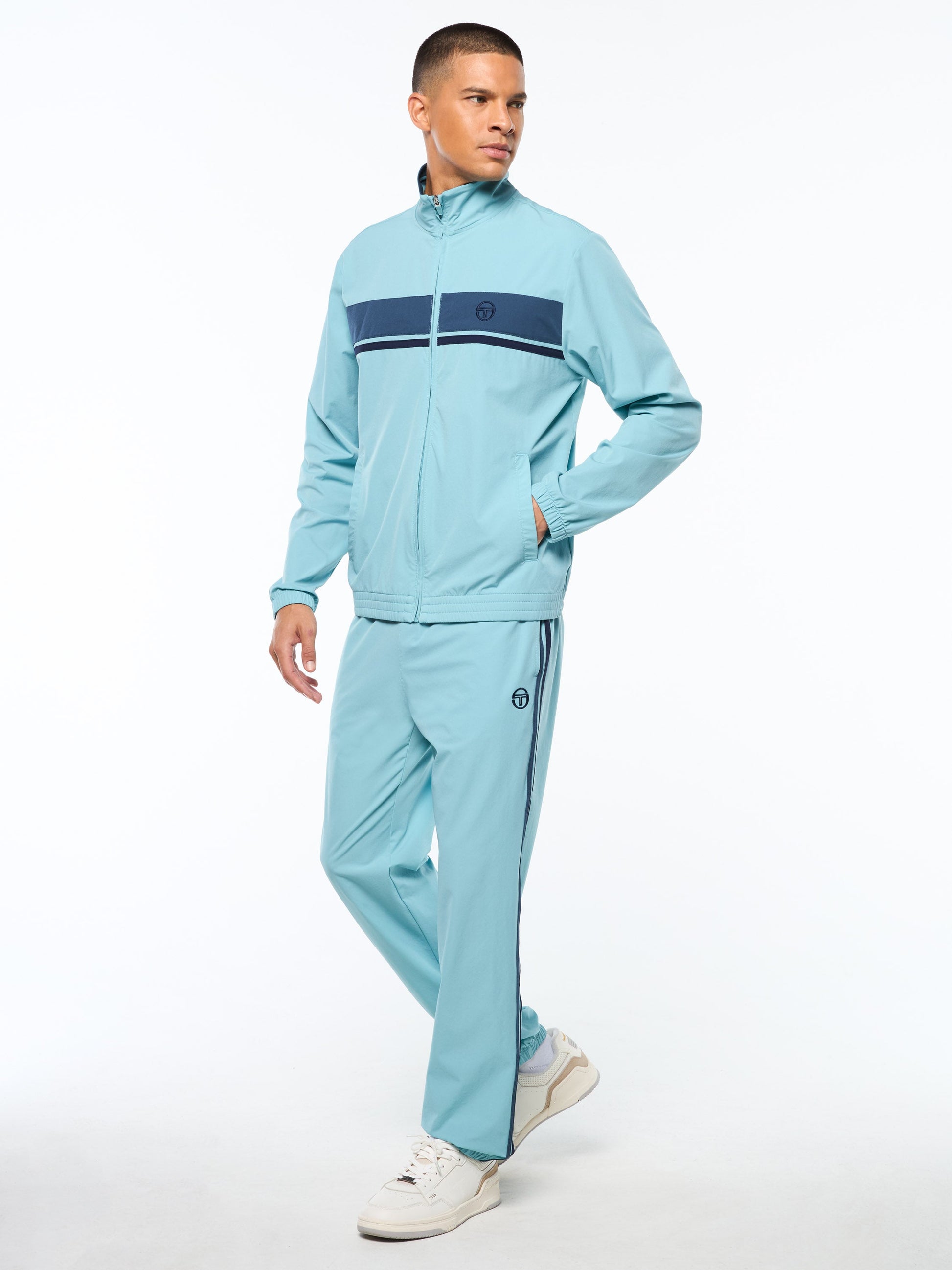 Man wearing a light blue tracksuit with a dark blue stripe on a white background