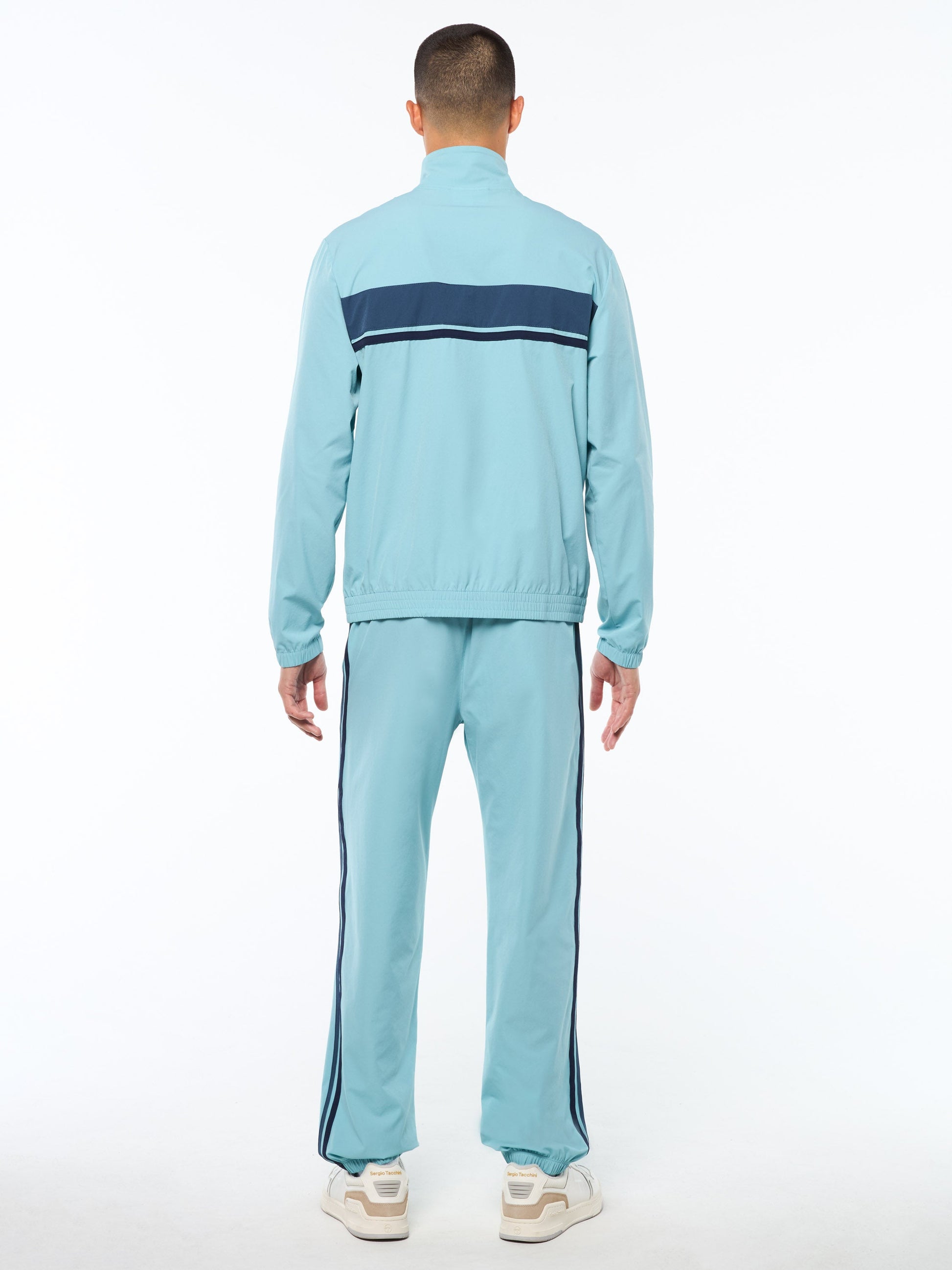 Person wearing a light blue tracksuit with a navy stripe on a white background