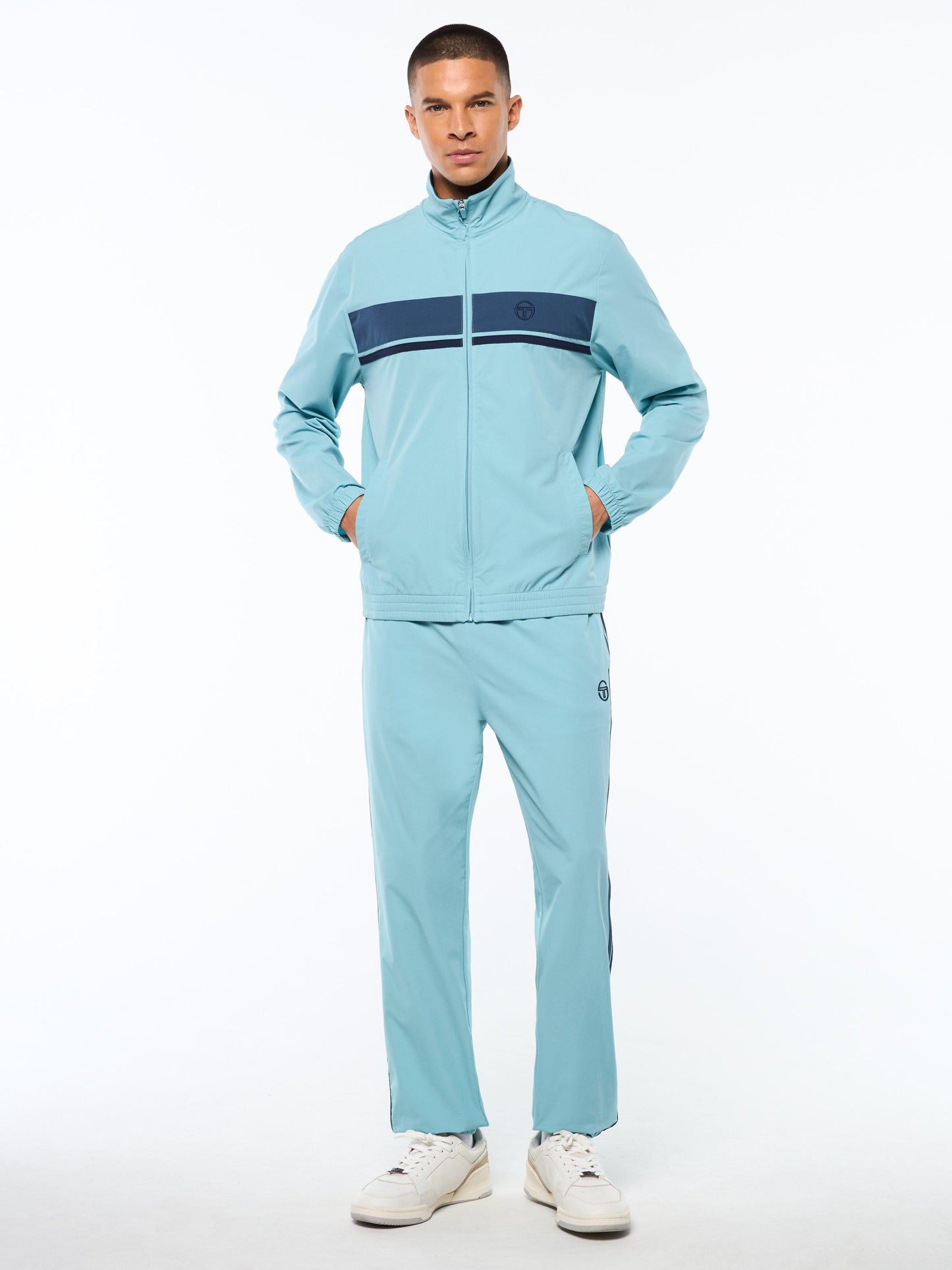 Man wearing a light blue tracksuit with a dark blue stripe on a white background