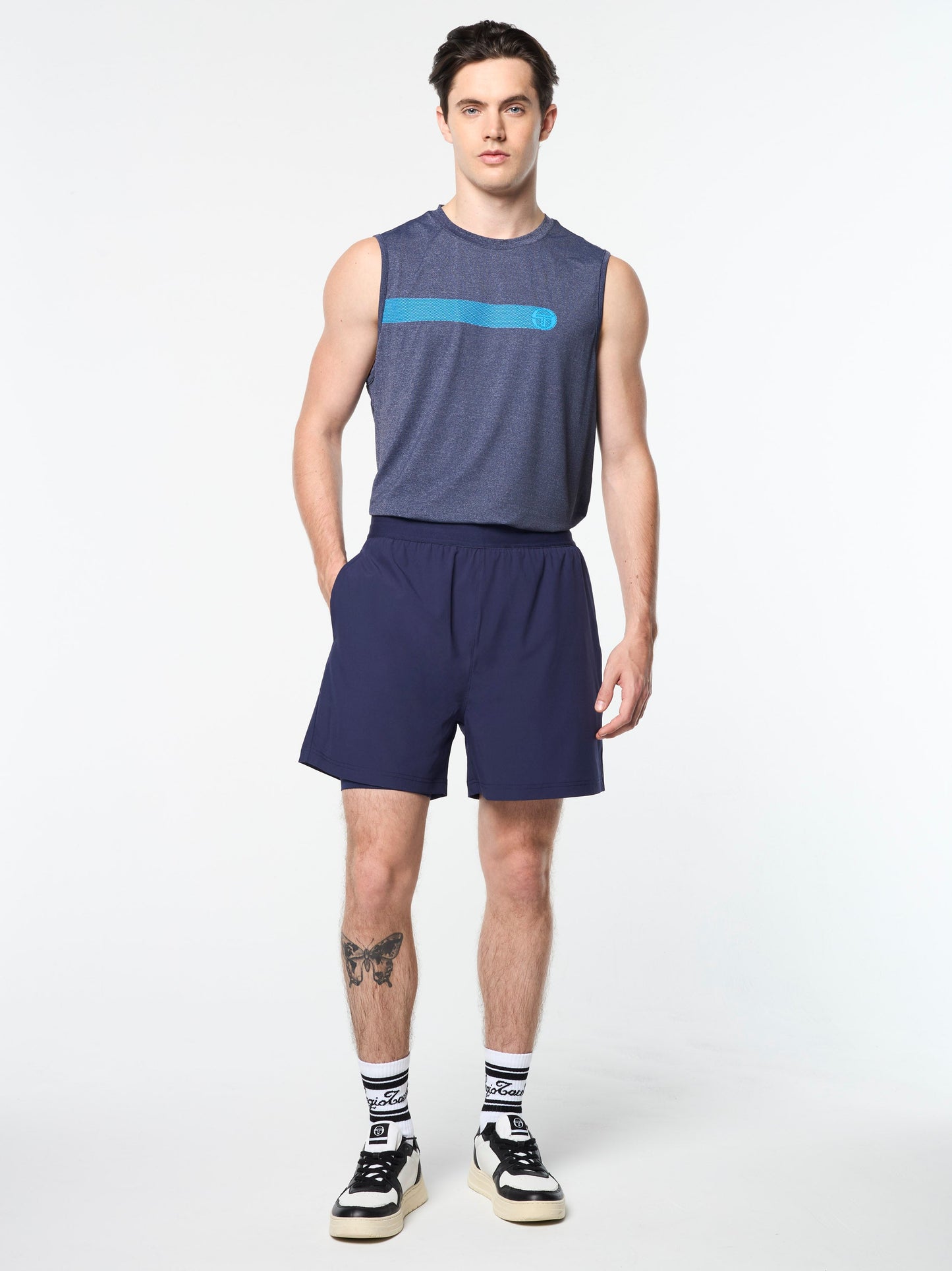 Man wearing a sleeveless blue top and shorts on a white background