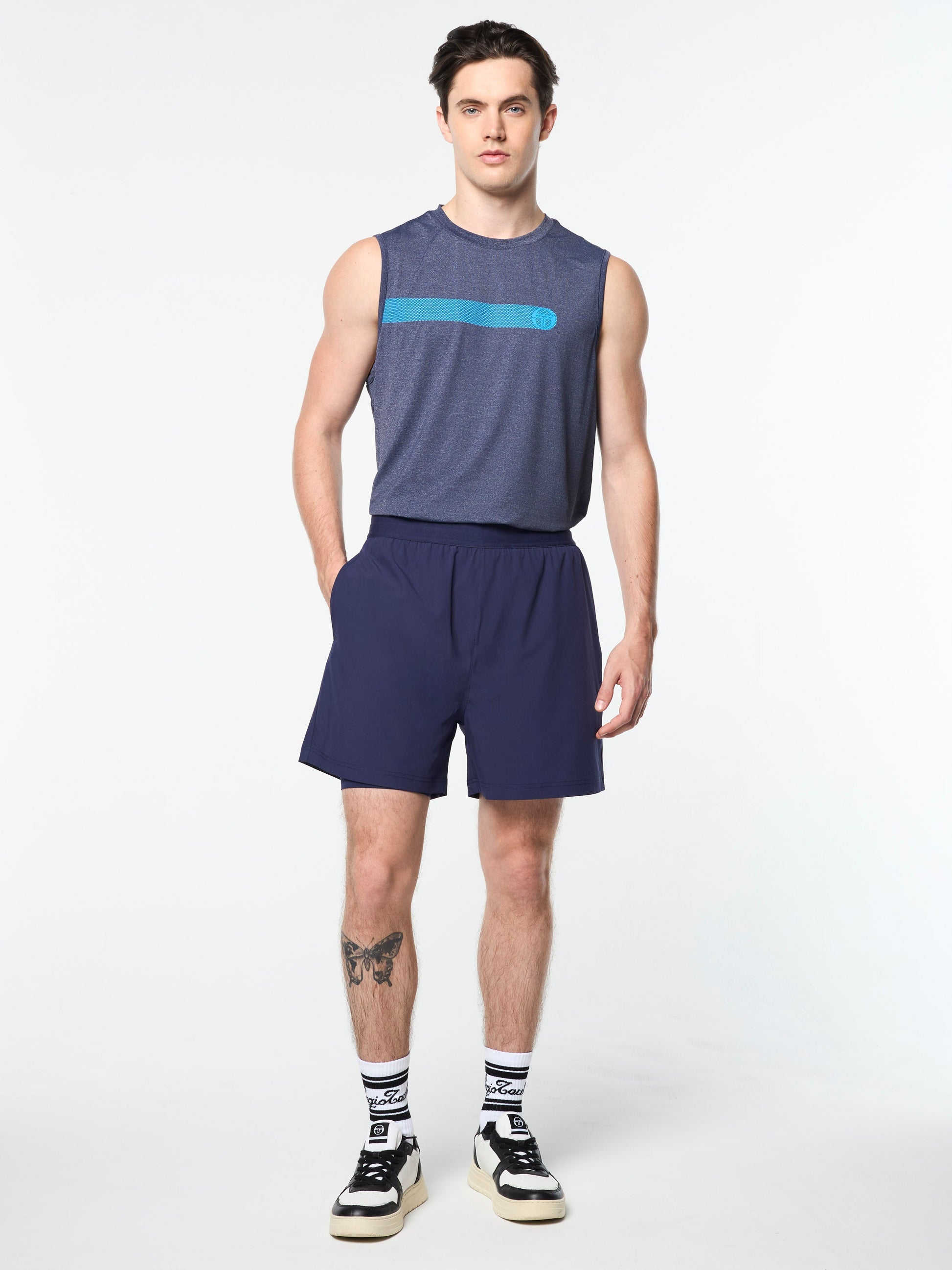 Man wearing a sleeveless blue top and shorts on a white background