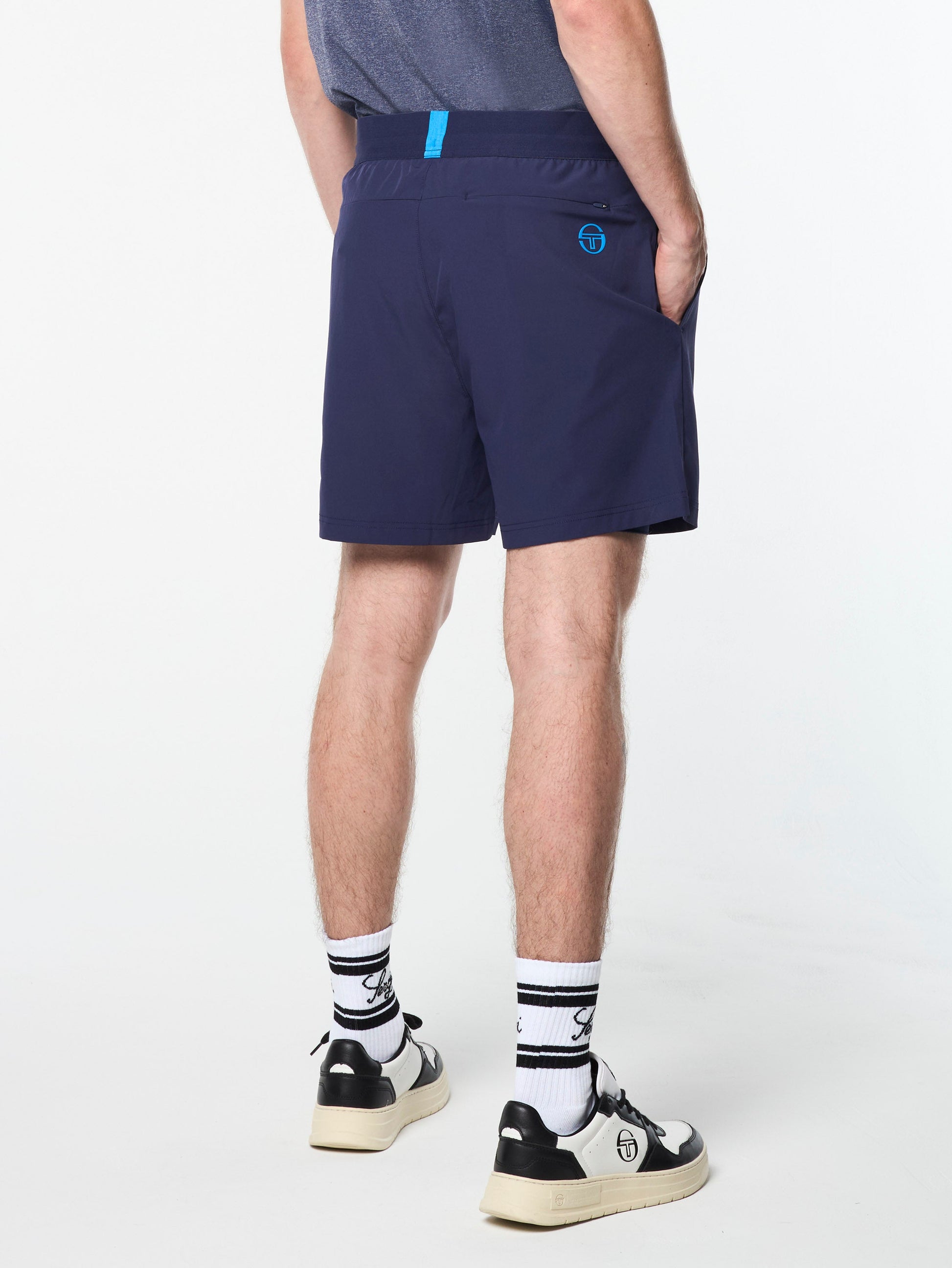 Person wearing navy shorts with a logo on a white background