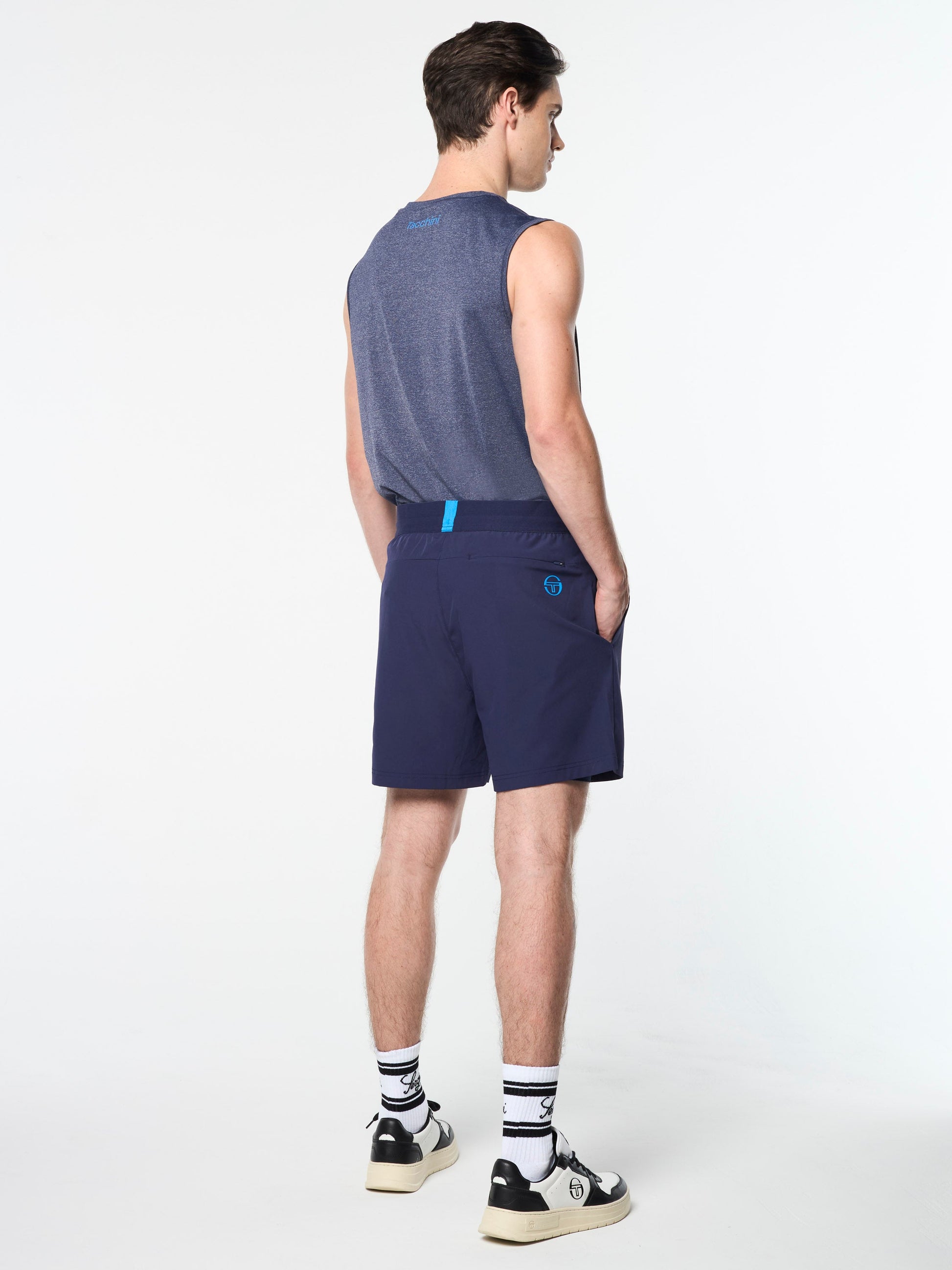 Person wearing a sleeveless shirt and navy shorts on a white background