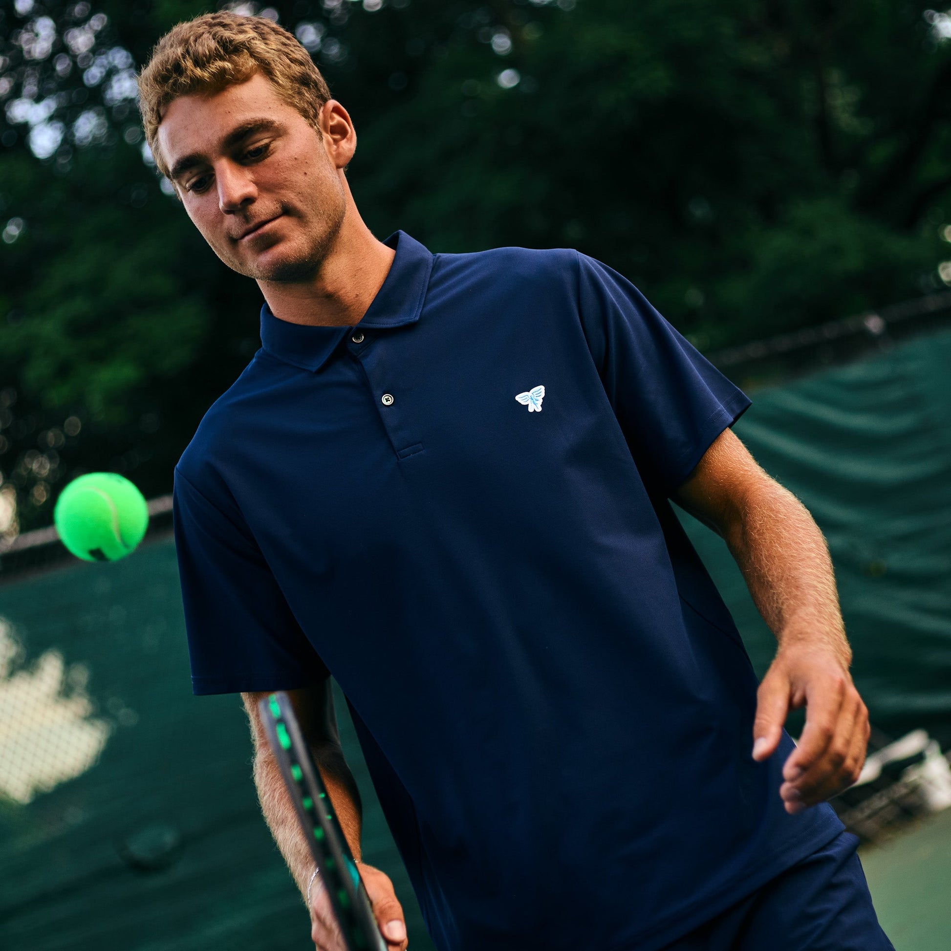 Man in a blue shirt holding a tennis racket on a tennis court