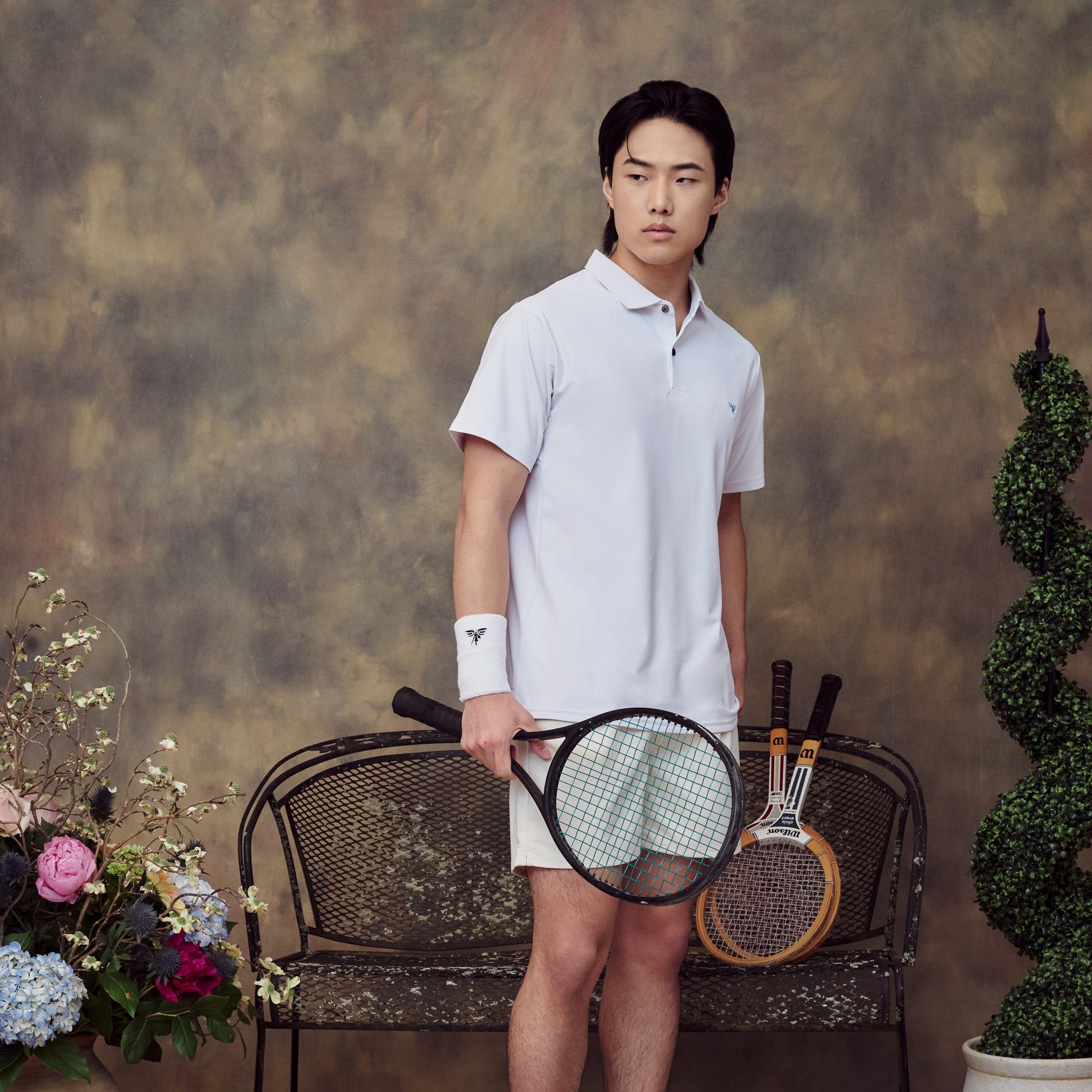 Person holding a tennis racket in a studio setting with decorative elements.