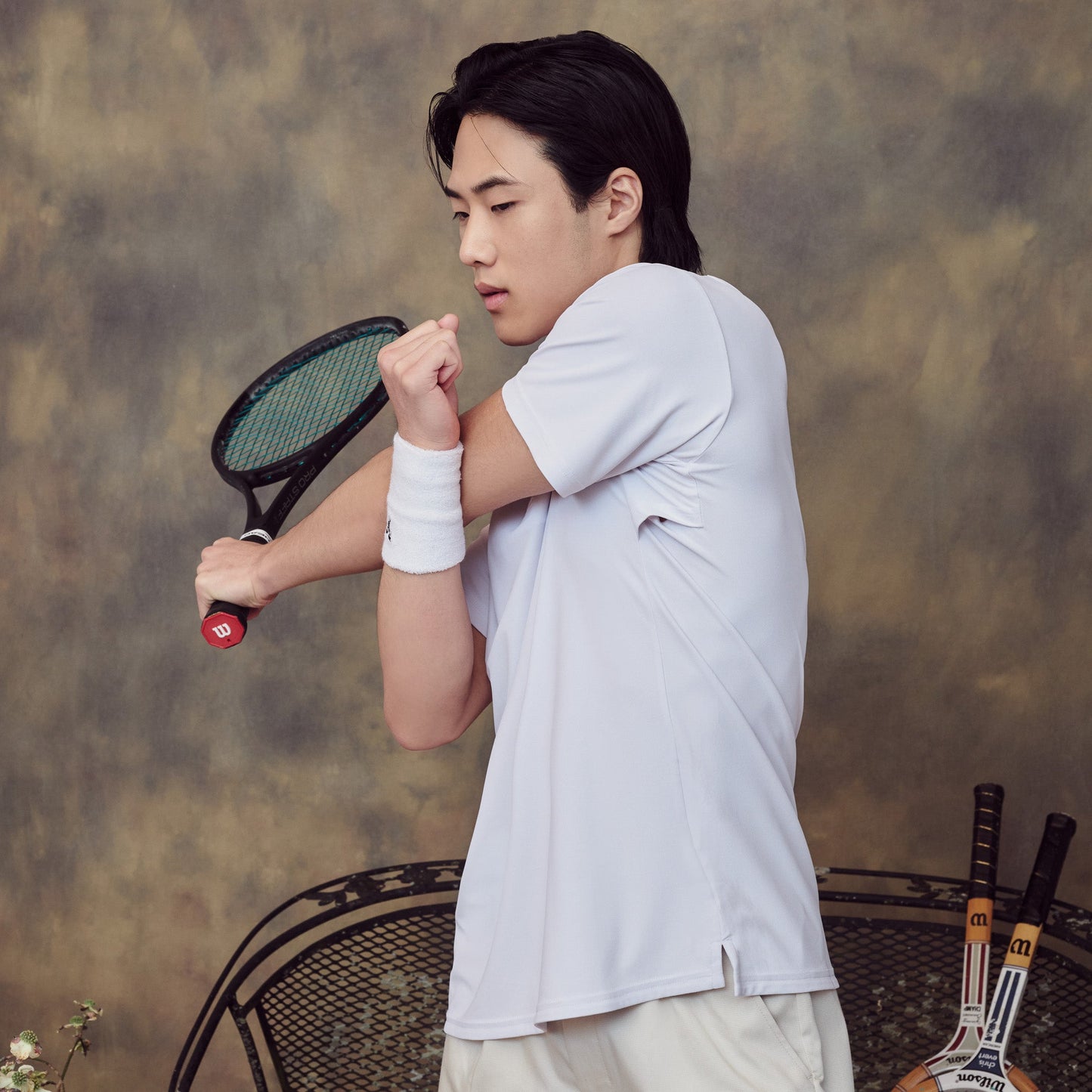 Person holding a tennis racket against a textured wall