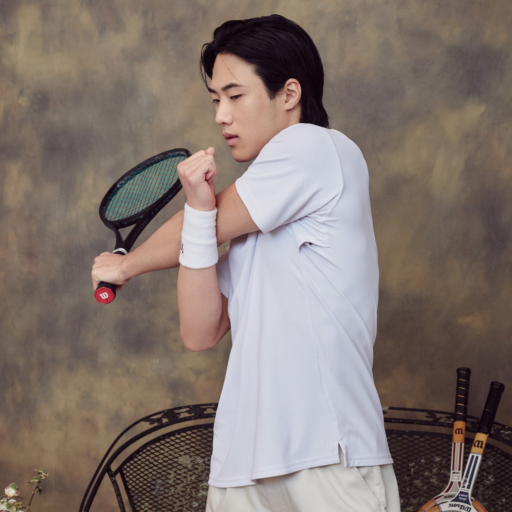 Person holding a tennis racket against a textured wall