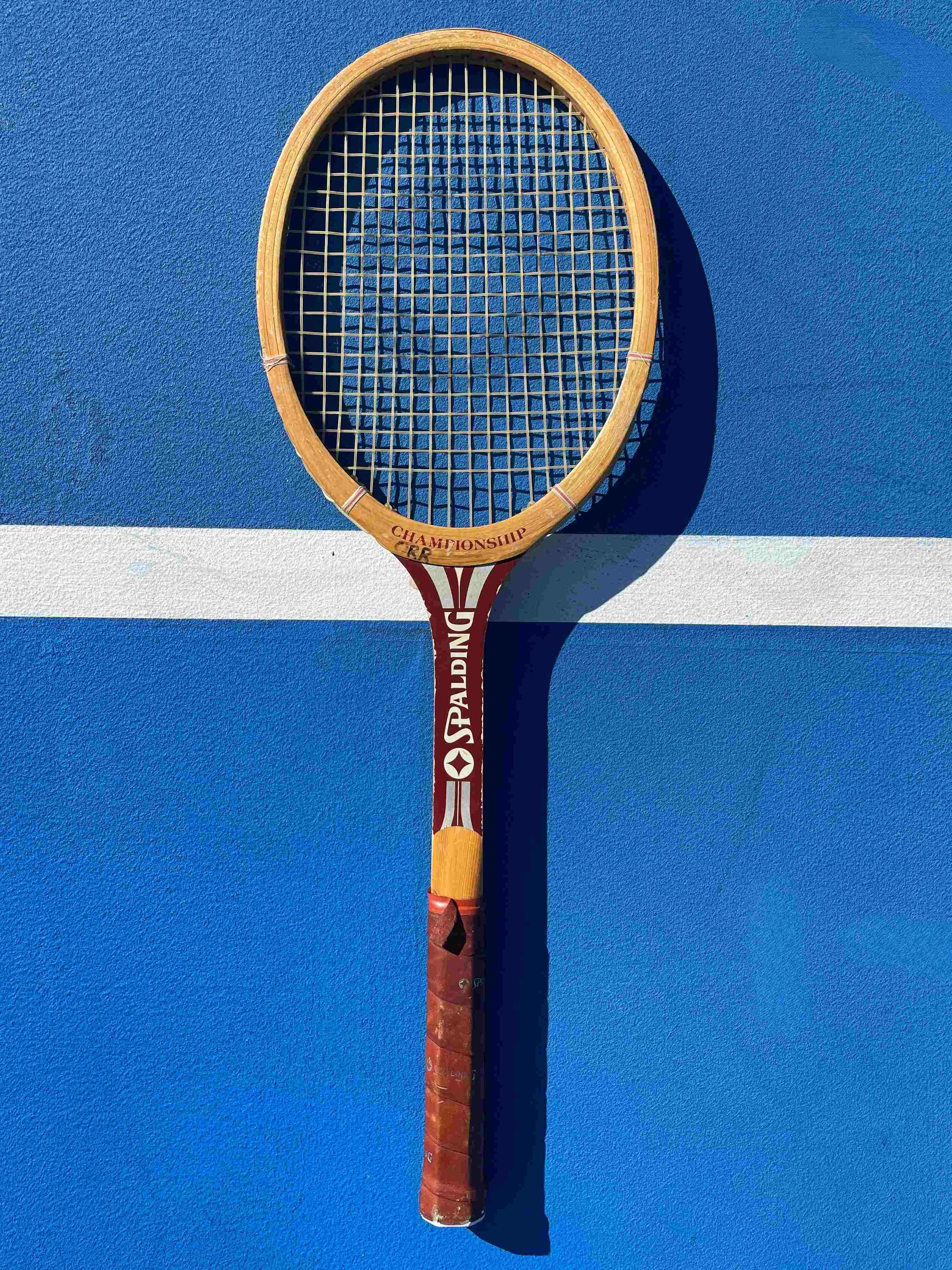 Vintage Spalding tennis racket on a blue court with white lines