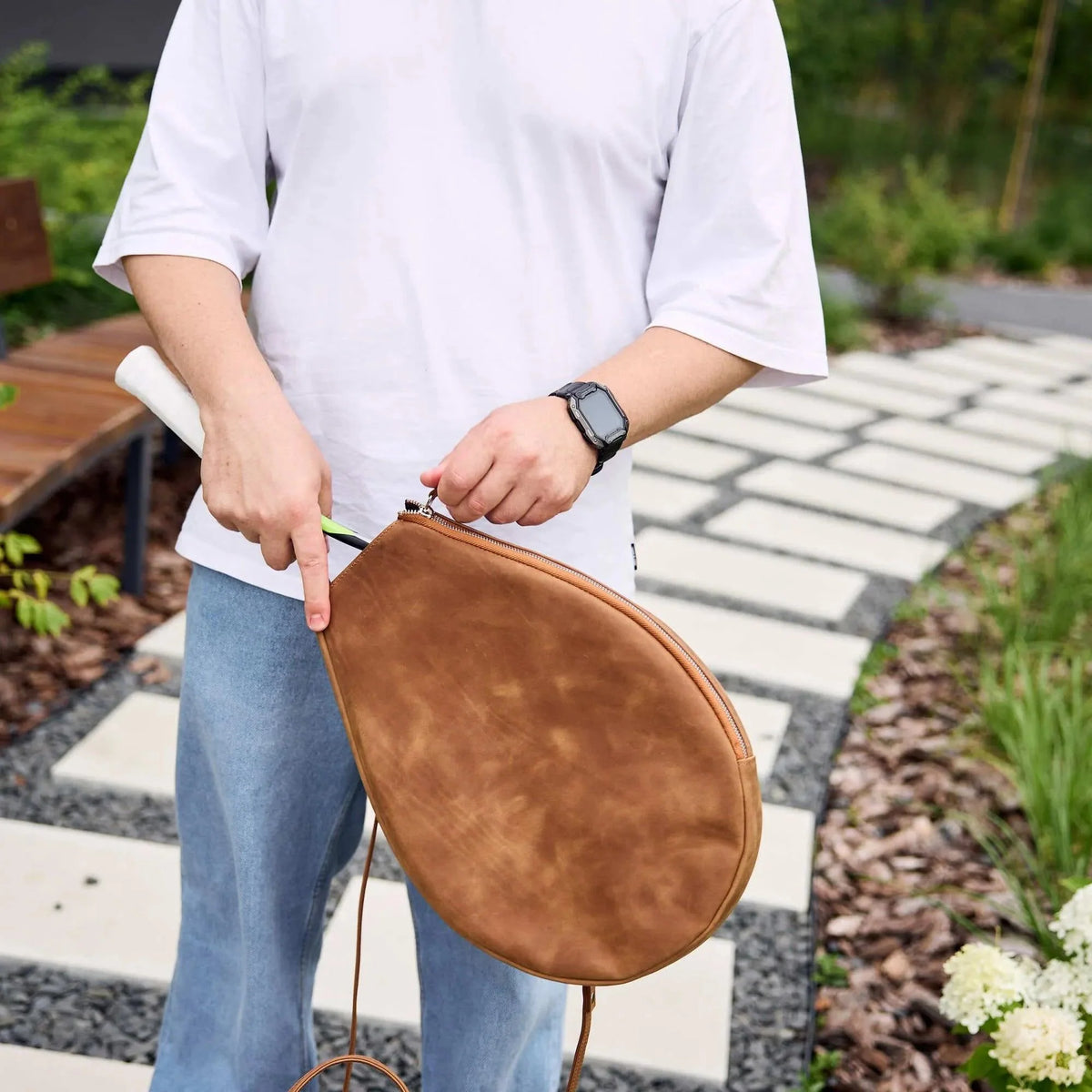 Woman holding Genuine leather bag with removable tennis racket cover.