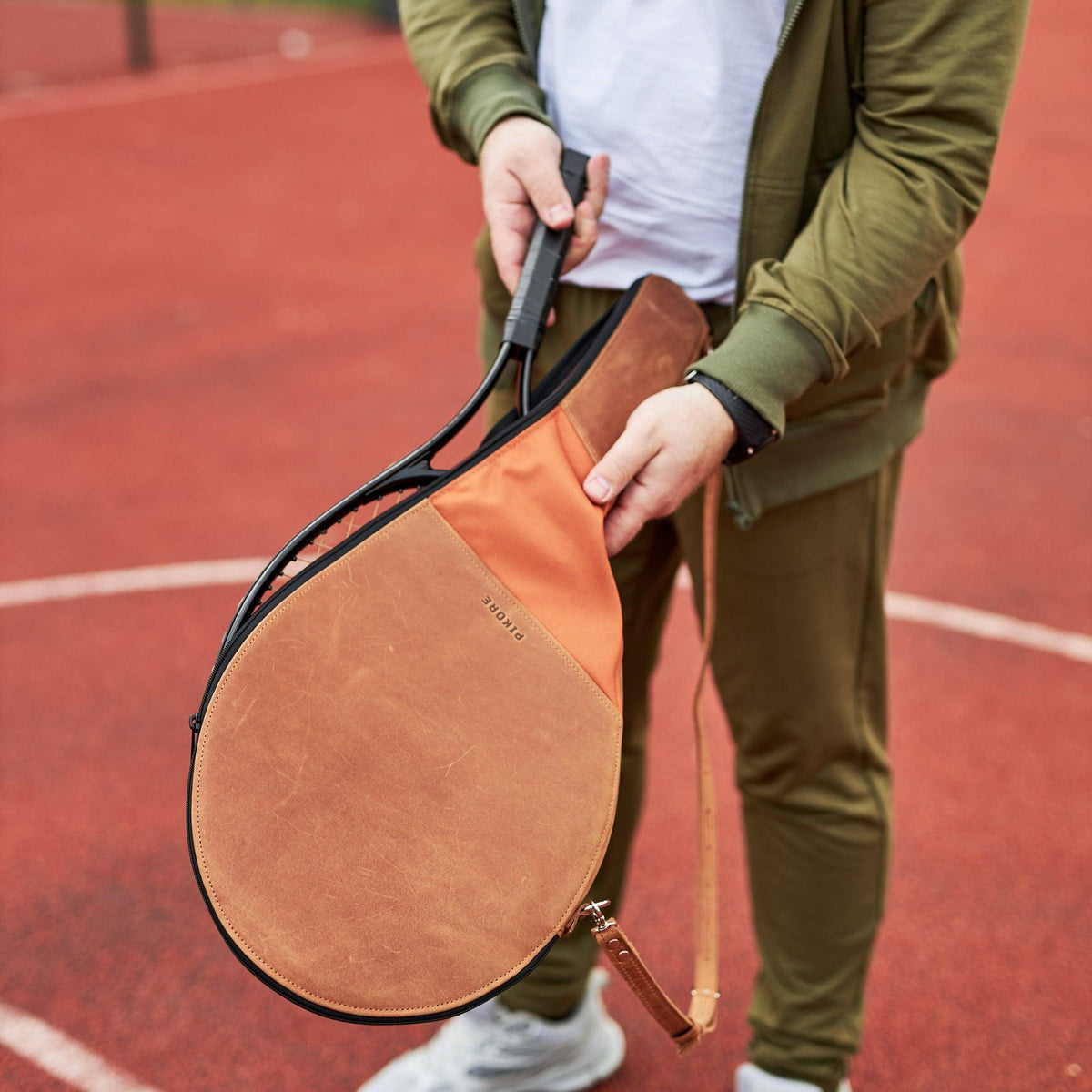 Man pulling a tennis racquet from a leather cover.