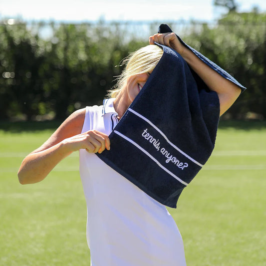 Femail tennis player holding Ame & Lulu navy Tennis Towel with "tennis anyone?" on TennisDuJour.com.