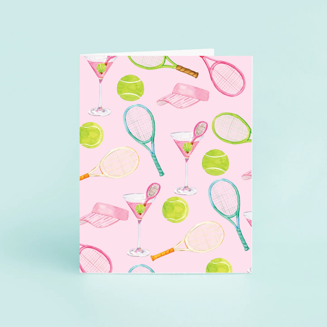Notebook with tennis racket, ball, and martini glass pattern on pink cover against a light blue background