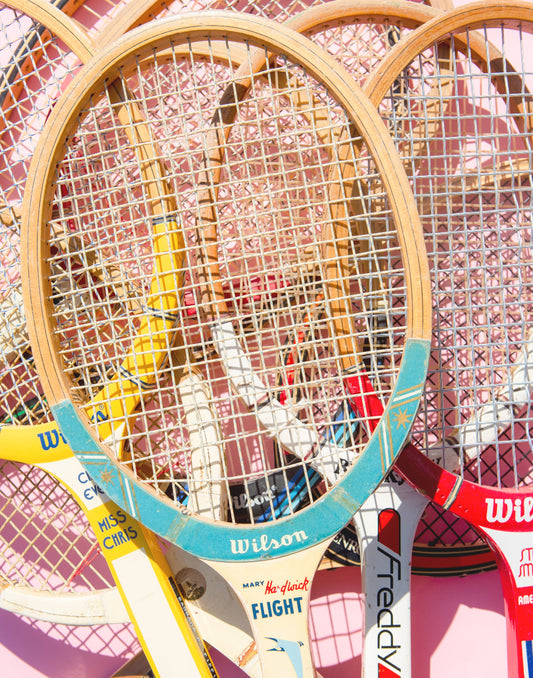 Vintage Tennis Racquets stacked on a pink tennis court. Artwork by Susan Johnson on TennisDuJour.com