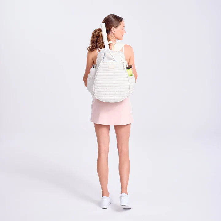 Woman wearing a white tennis backpack on a plain background