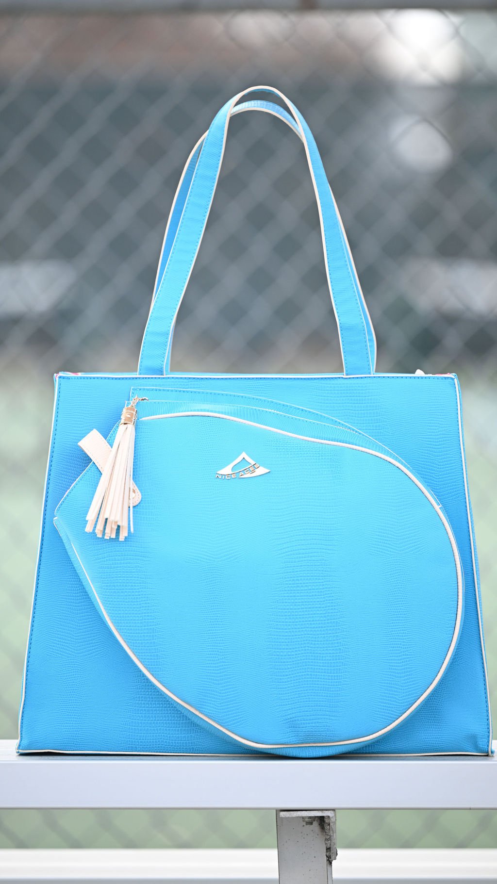 Blue tennis  tote bag with a tassel on a metal surface