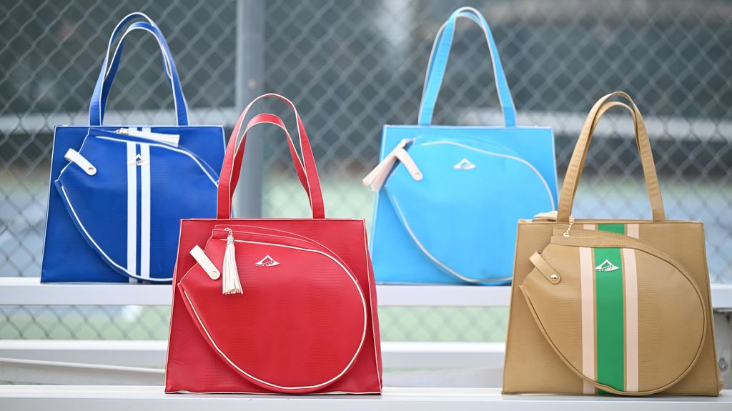 Four tennis bags in blue, red, and beige with a visible brand logo on a neutral background.